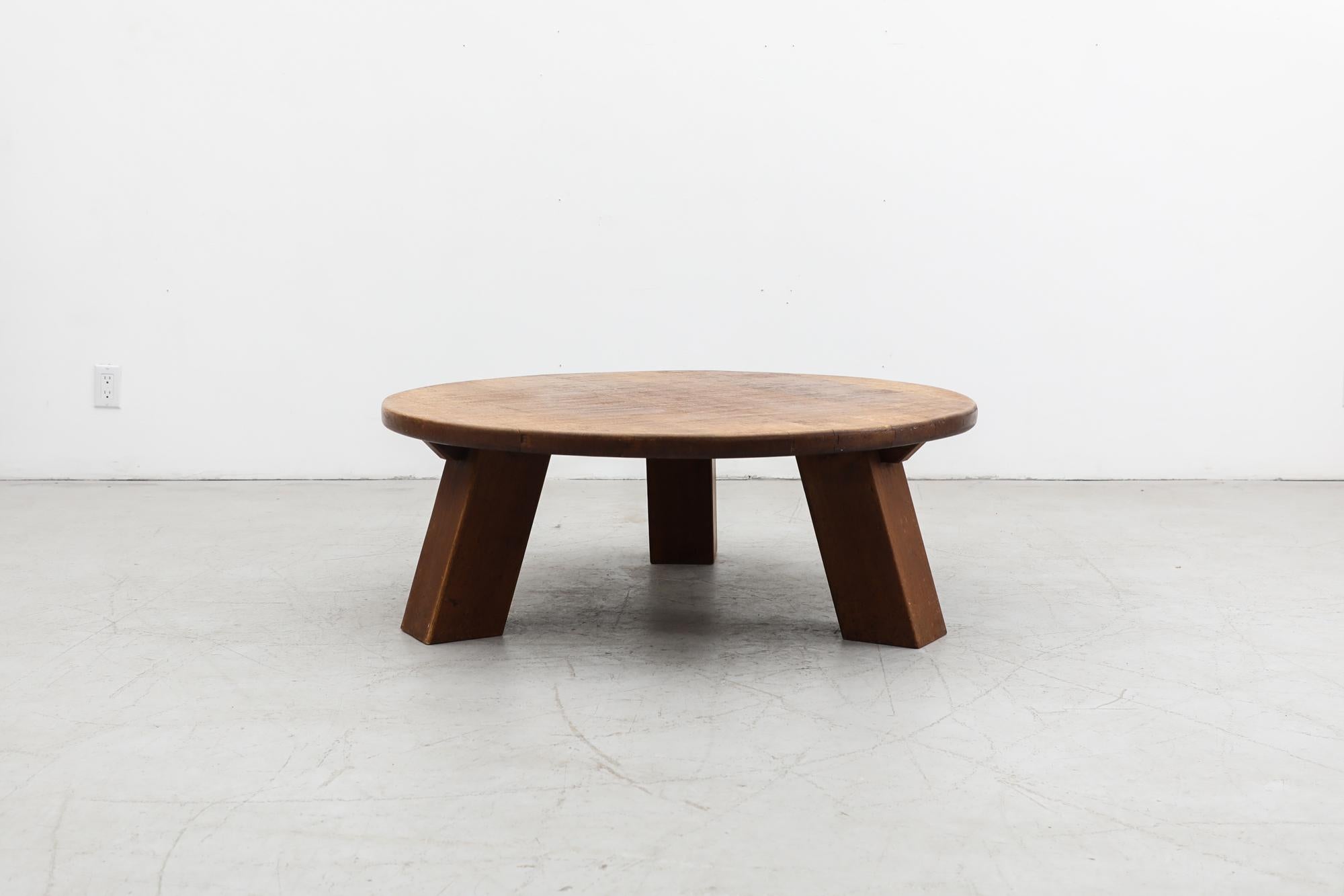 Heavy round Brutalist coffee table made from solid oak with three sturdy square legs. In very original condition with visible wear and patina consistent with its age and use. Other similar tables available and listed separately.