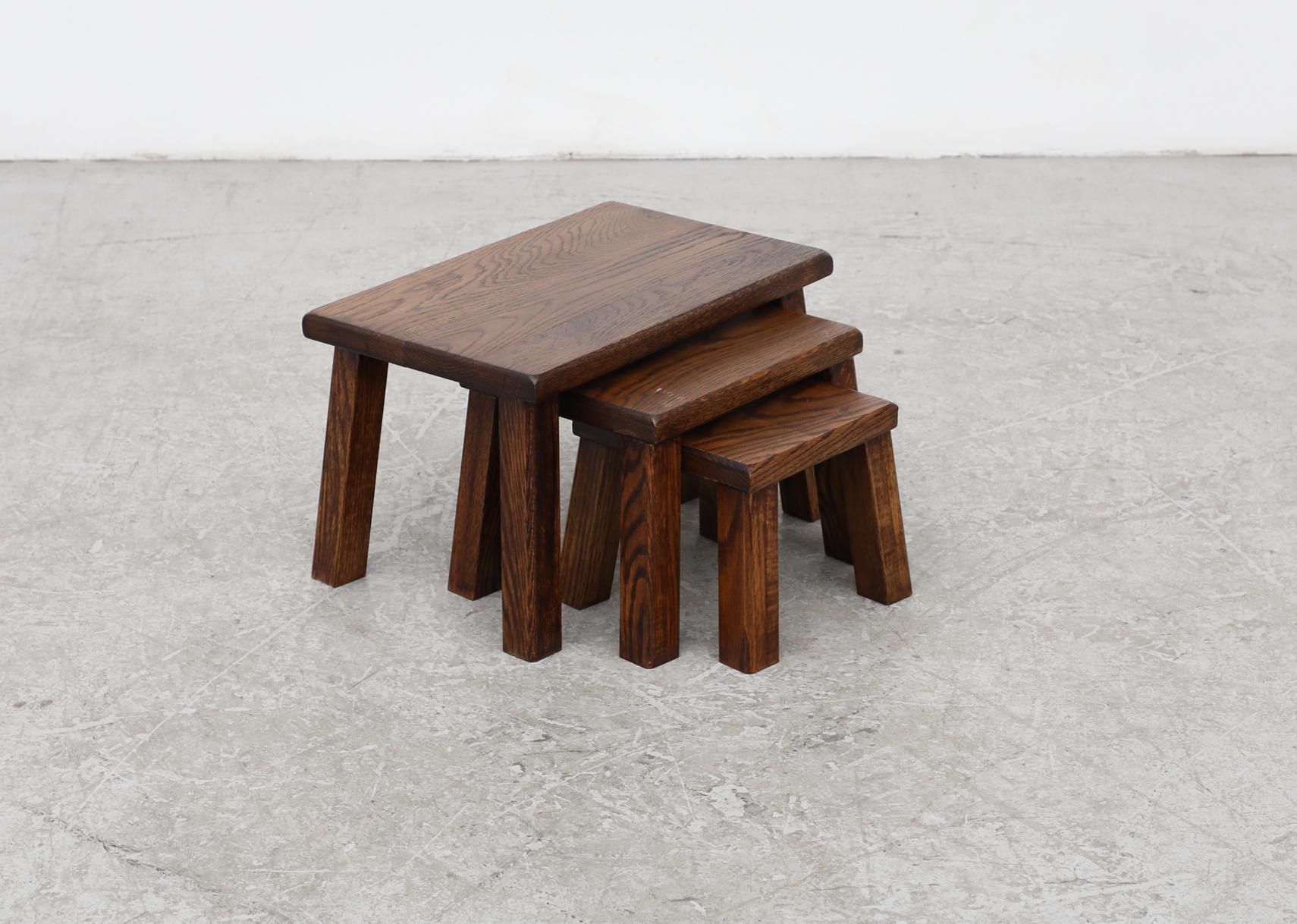 Ensemble de 3 tables gigognes Brutalist en chêne foncé avec des plateaux épais et de gros pieds angulaires carrés. En état d'origine, avec une usure visible et une patine correspondant à leur âge et à leur utilisation.