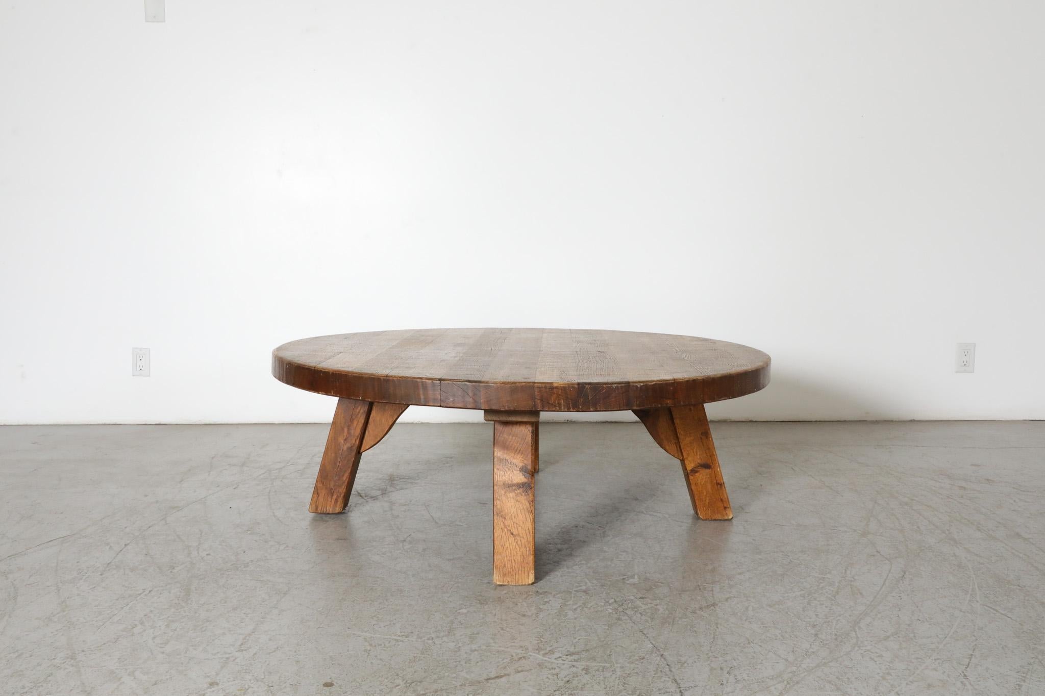 Brutalist, heavy round coffee table is made from solid oak and has three sturdy square legs. Reminiscent of the work of Pierre Chapo, the French post war designer that worked extensively with wood. In original condition with visible wear and patina