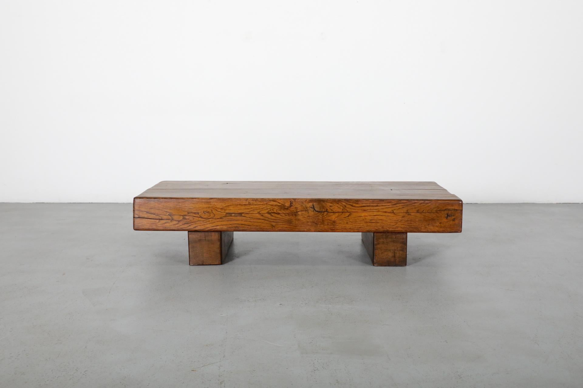Brutalist low, rectangular coffee table with gorgeous patina. This table is made from heavy, solid oak with two thick legs and top. In original condition with visible wear, including scratches and natural separation. Wear is consistent with age and