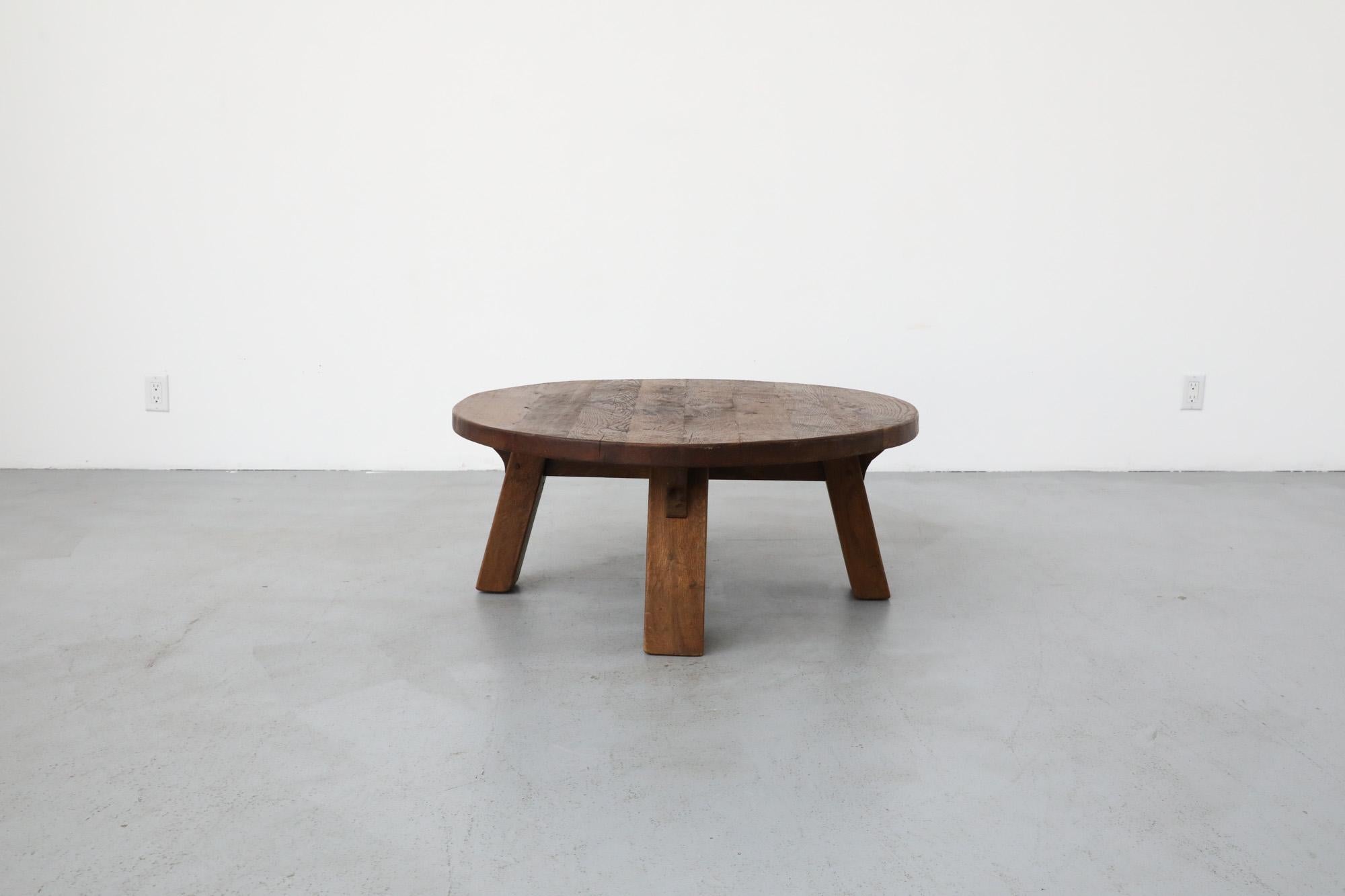 This Brutalist Pierre Chapo style coffee table is made from solid oak, with a round top and rectangular legs. In original condition with visible wear, including some natural cracking. Wear is consistent with its age and use.
