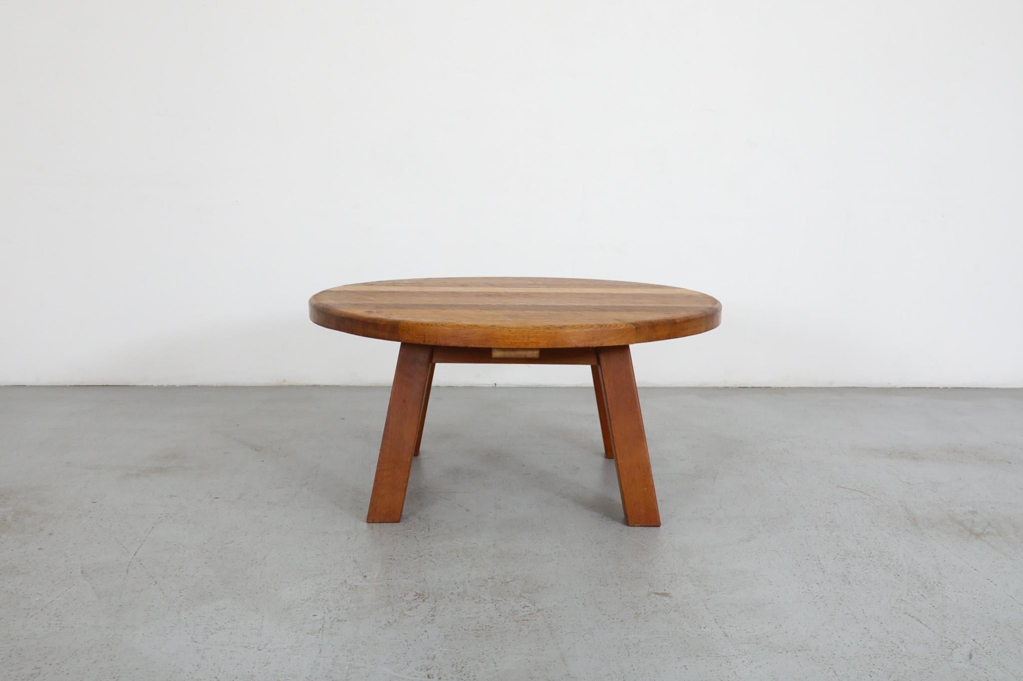 Table basse en chêne inspirée par Pierre Chapo, avec des variations dans les planches qui sont assemblées pour former l'épais plateau rond ; y compris des planches plus foncées, plus claires, et d'autres avec une figuration sauvage. Légèrement