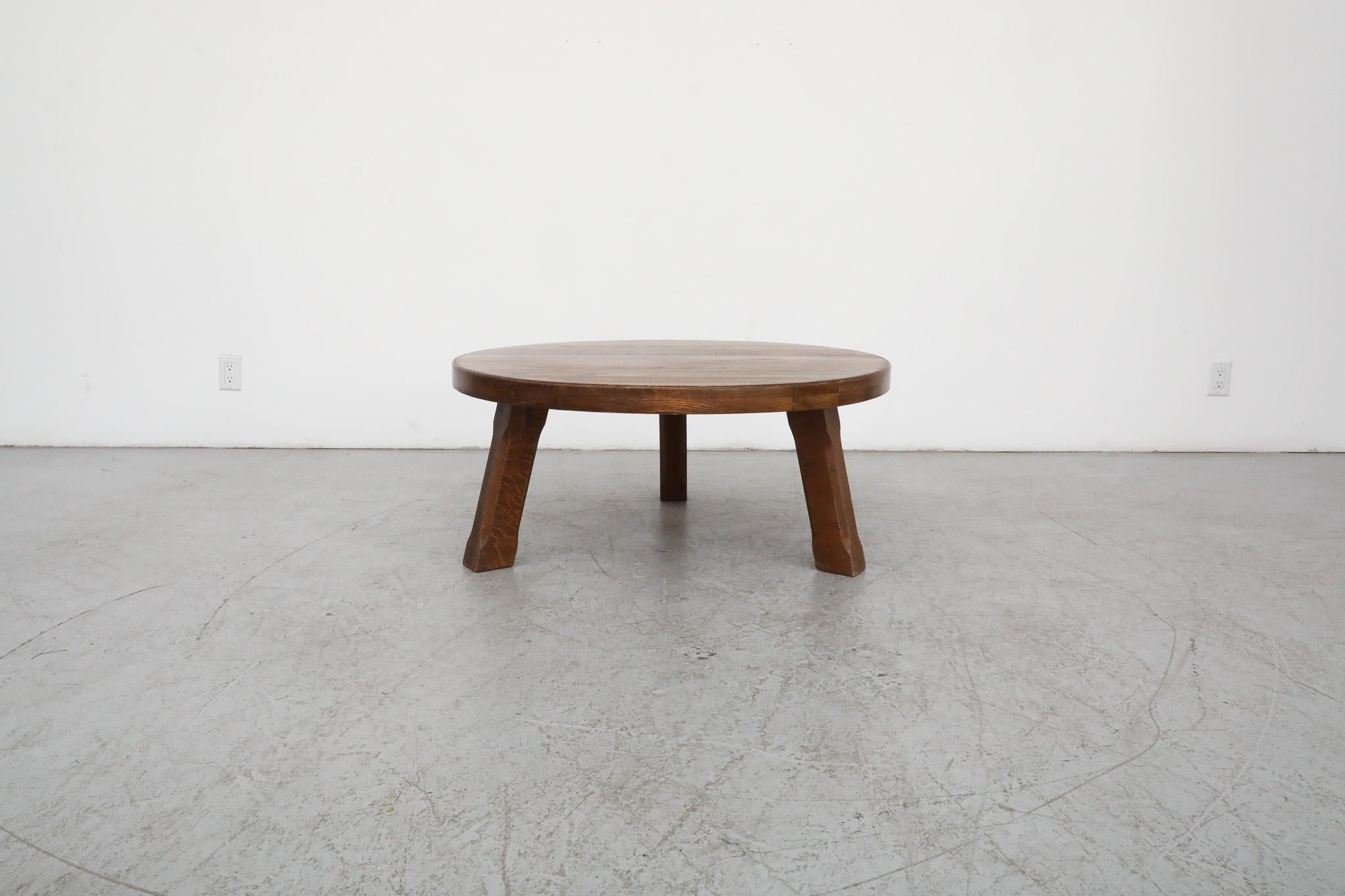 This Brutalist Pierre Chapo style coffee table is made from very sturdy solid oak, with a generously sized round top and subtly carved tripod legs. It is in original condition with some visible wear, including some natural cracking. Wear is