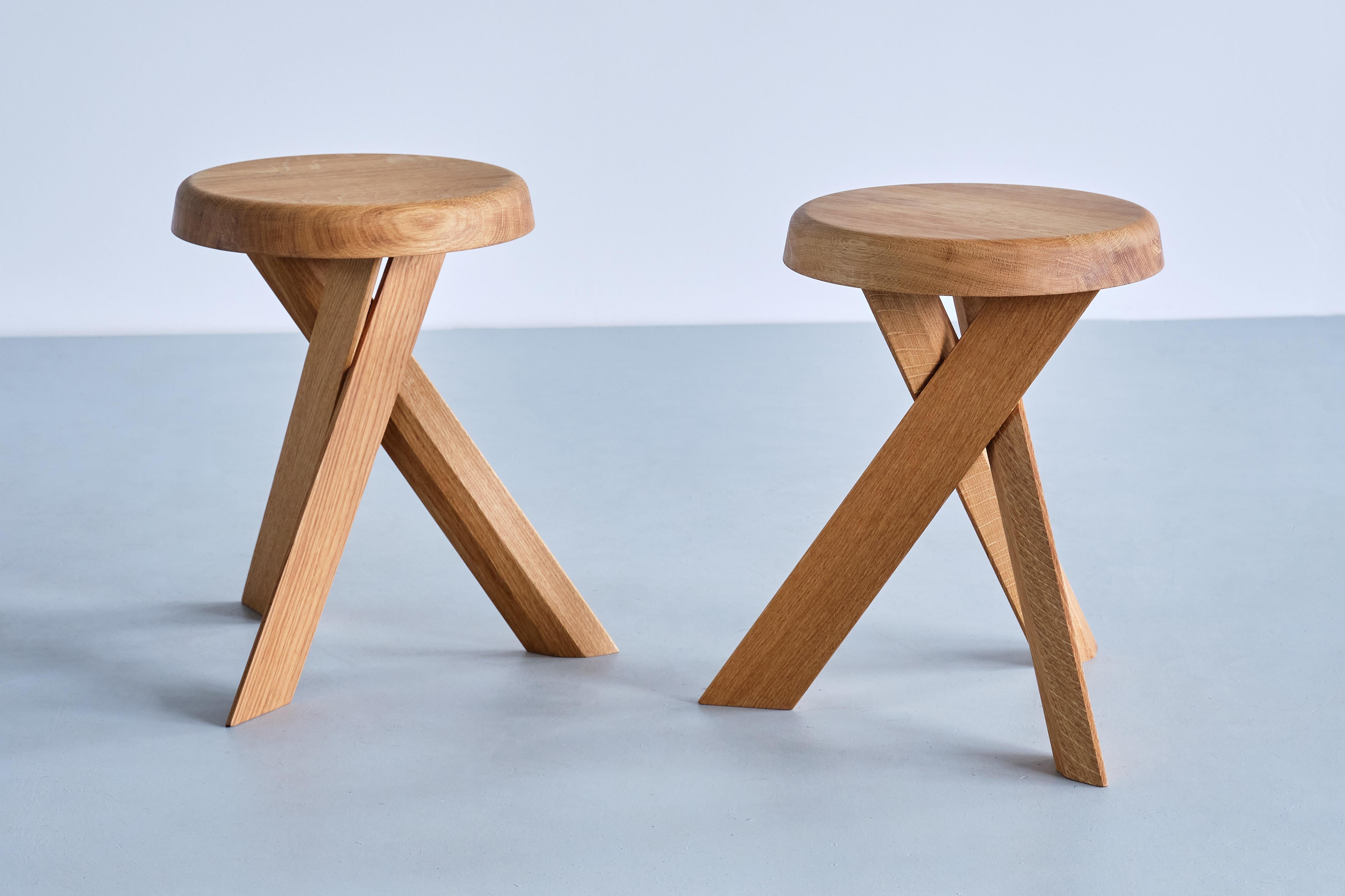 This striking three-legged stool is the model S31 designed by Pierre Chapo in 1974. The cross legged base and round seat are in solid oak wood. This stool also could function as a small side table.  
This listing is for the S31A (lower) version in