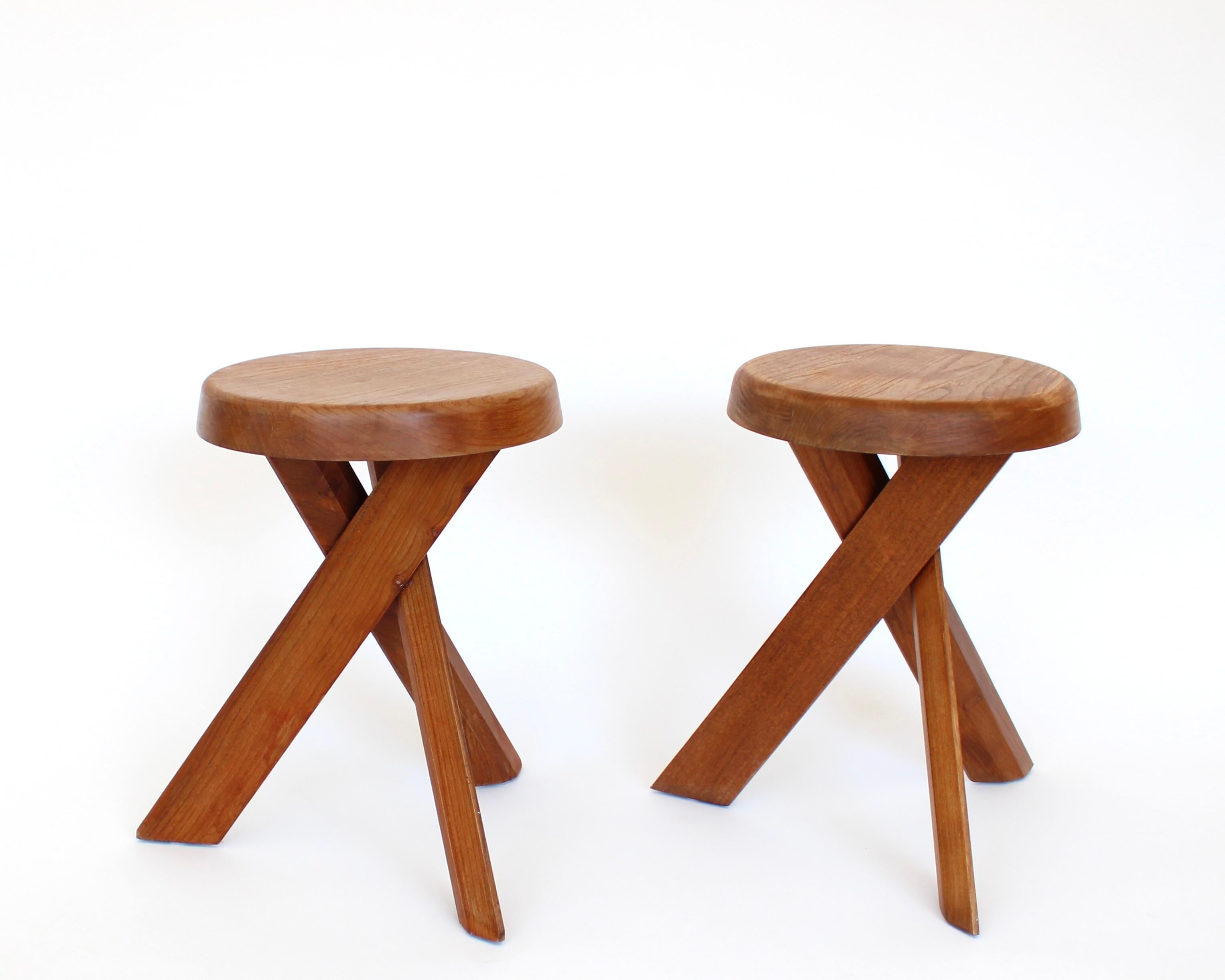 Early edition stools by Pierre Chapo, meticulously crafted from solid elm feature a thick seating with natural veining and three crossed feet. Visible joints along the seating's edge are typical of Pierre Chapo's creations. The base of the stool,