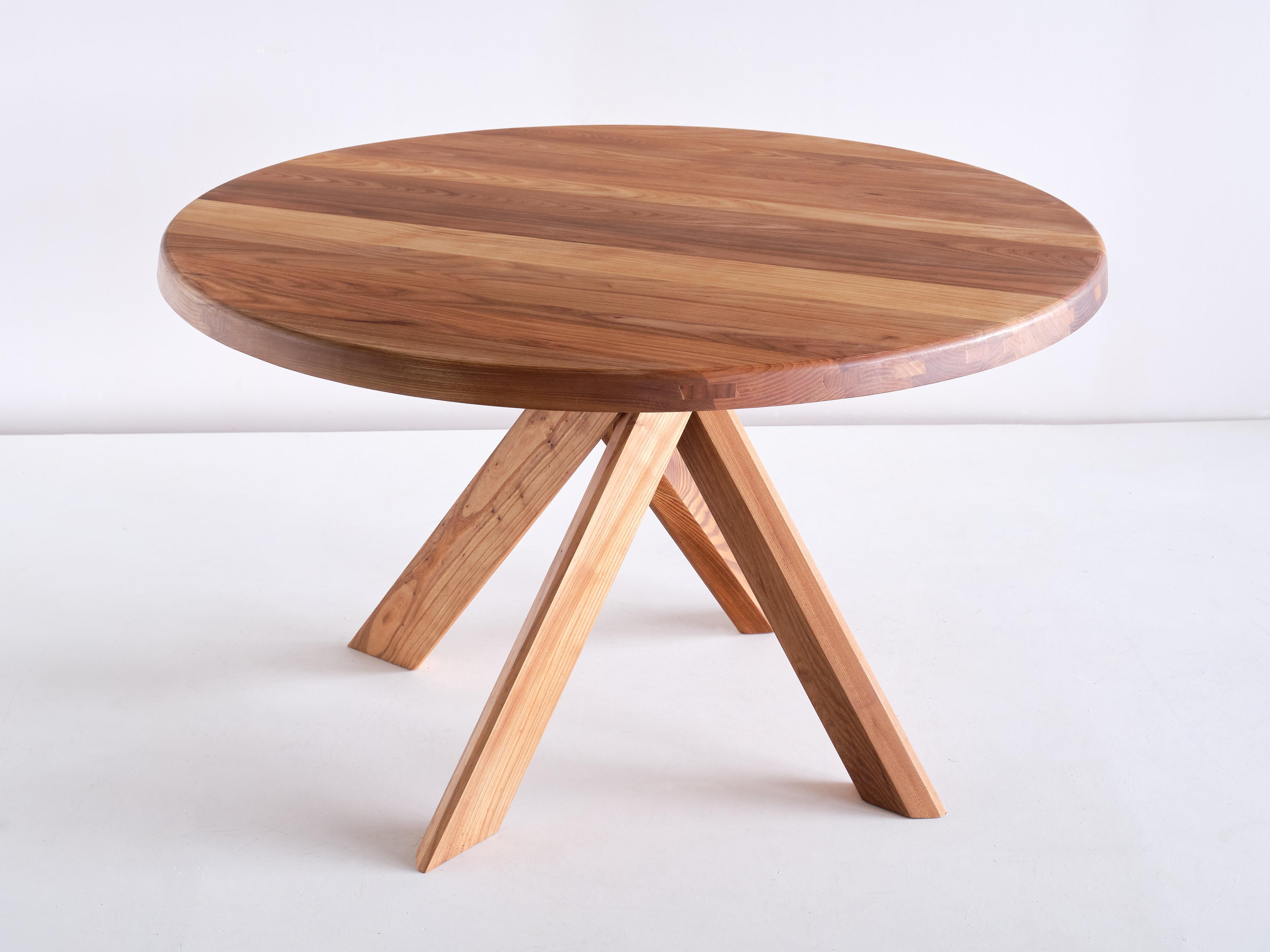 This iconic dining table is the model T21B designed by Pierre Chapo in 1973. The table is made of solid elm wood with a beautiful grain. Striking four legged cross base and round table top. 

This new table was made by Chapo Creation, now run by