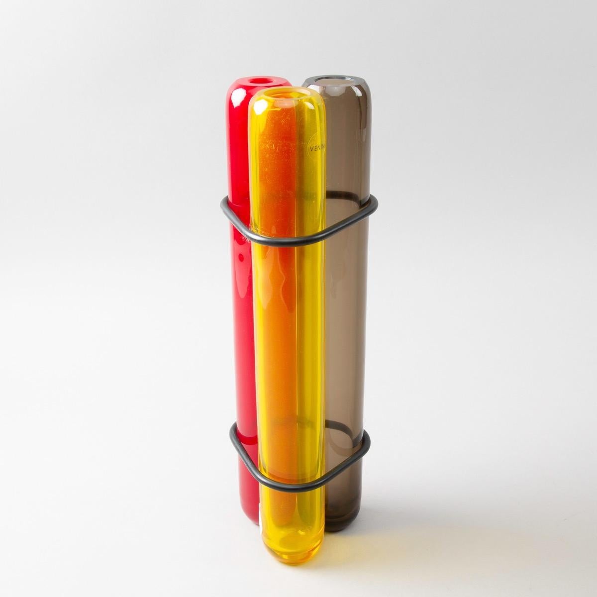 A rare vase designed by Pierre Charpin in 2003, manufactured the same year at Venini.

A very simple and efficient idea of 3 mouth blown glass (dark amber, red and yellow) tubes joined together with rubber o-rings.

The piece is signed with
