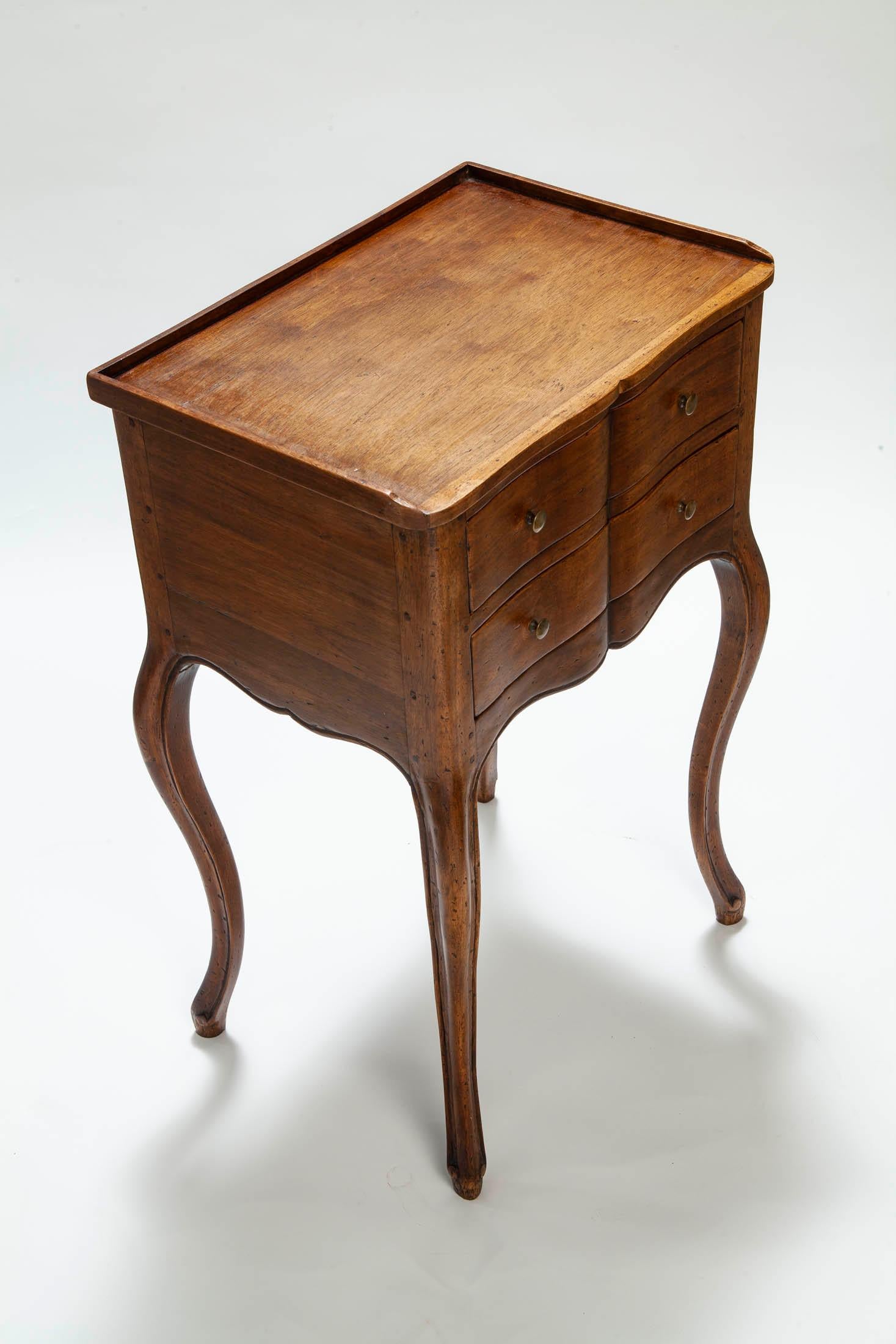 Charming little side table features serpentine drawers with small brass knobs. Raised edge surrounding the top. The table is supported on cabriole legs.
The apron is scalloped on the front and side panels.