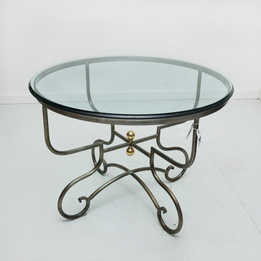 A wrought steel and glass round table, with scrolled legs and brass ball finials, retailed by Pierre Deux and manufactured by Arrowsmith Forge. 20th century stamped 