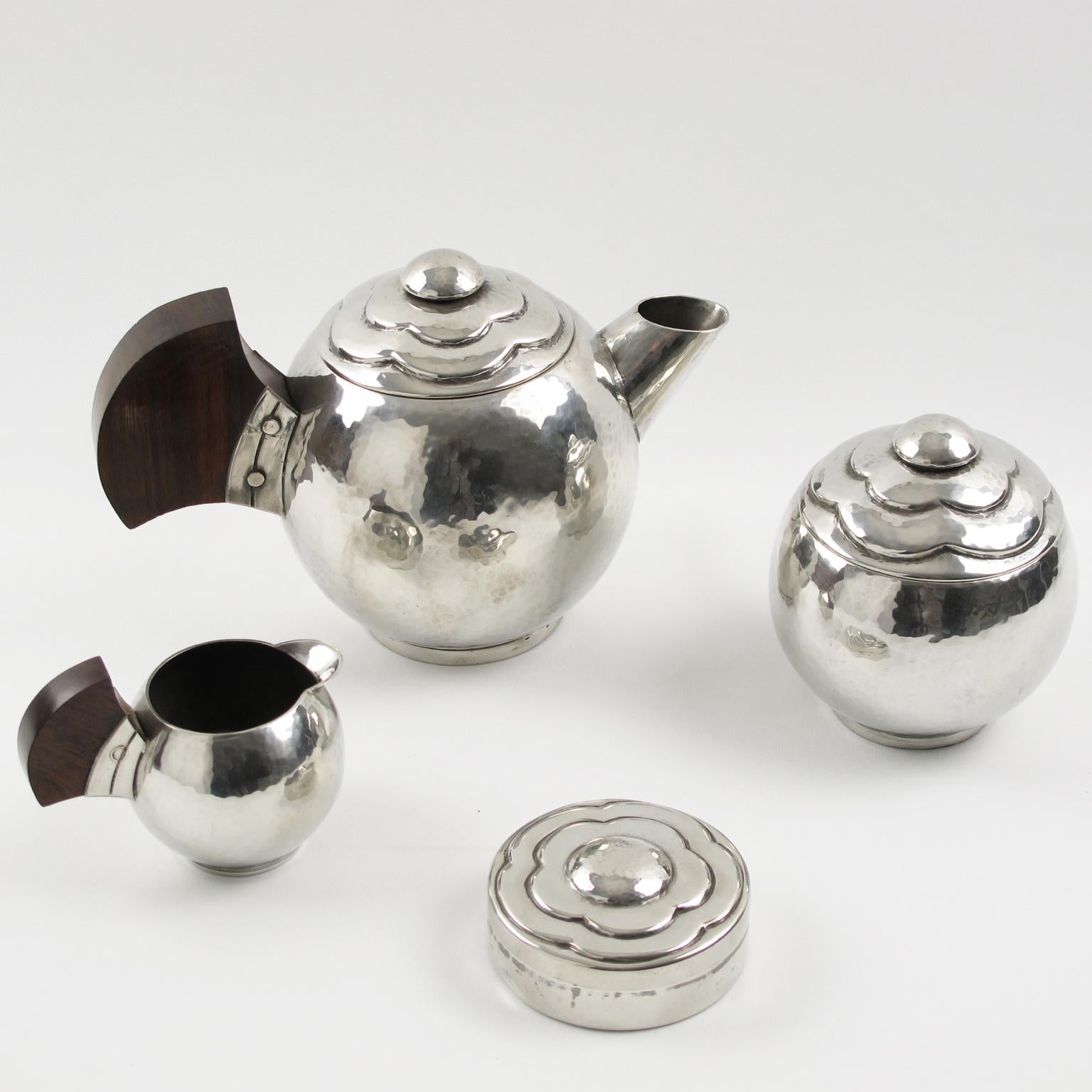 Elegant polished pewter tea or coffee set of 4 pieces by Pierre-Lucien DuMont, France. Set is build with coffee or teapot, sugar pot with lid, creamer and round box. Modernist rounded shape with slight hammered pattern and embossed stylized flower