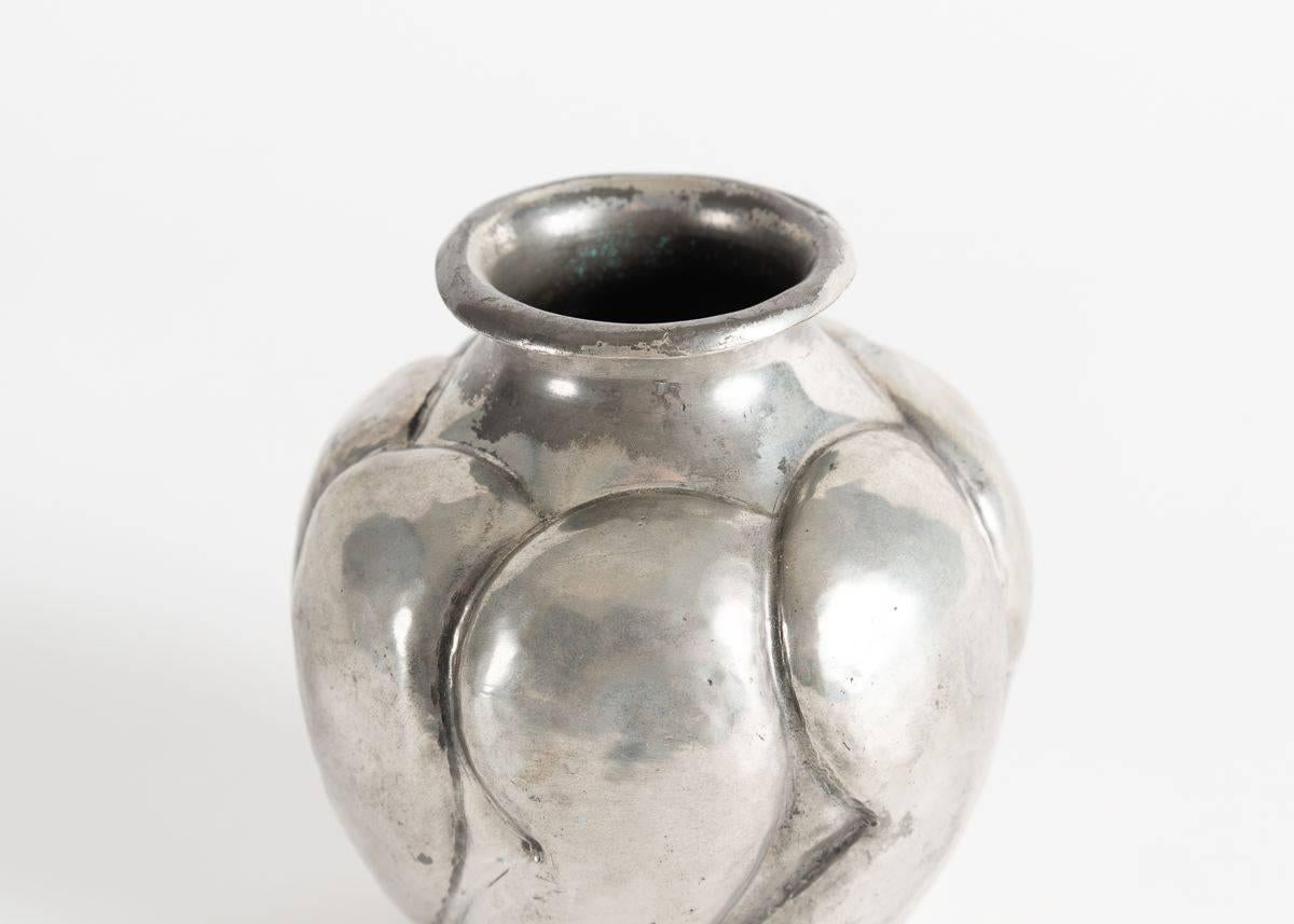 Signed: Dumont

Completed by Pierre DuMont, circa 1930, this charming vase in silvered metal possesses a plump form, and an elegant, unfurling lip, and features a motif of repeating and overlapping shapes that catch and reflect light in a