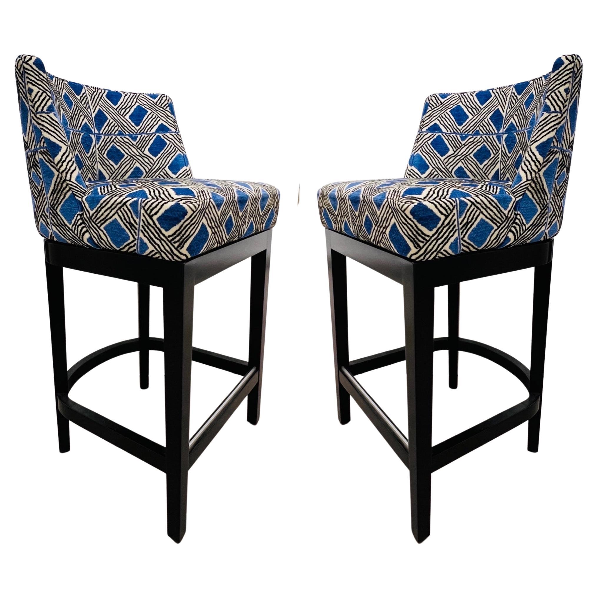 Pair of counter bar stools by La Maison Pierre Frey.  Mid-Century Modern design featuring swivel seats with curved backs.  Upholstered in Behanzin fabric, a woven chenille with geometric tribal patterns in blue and black over a beige ground.  Woven
