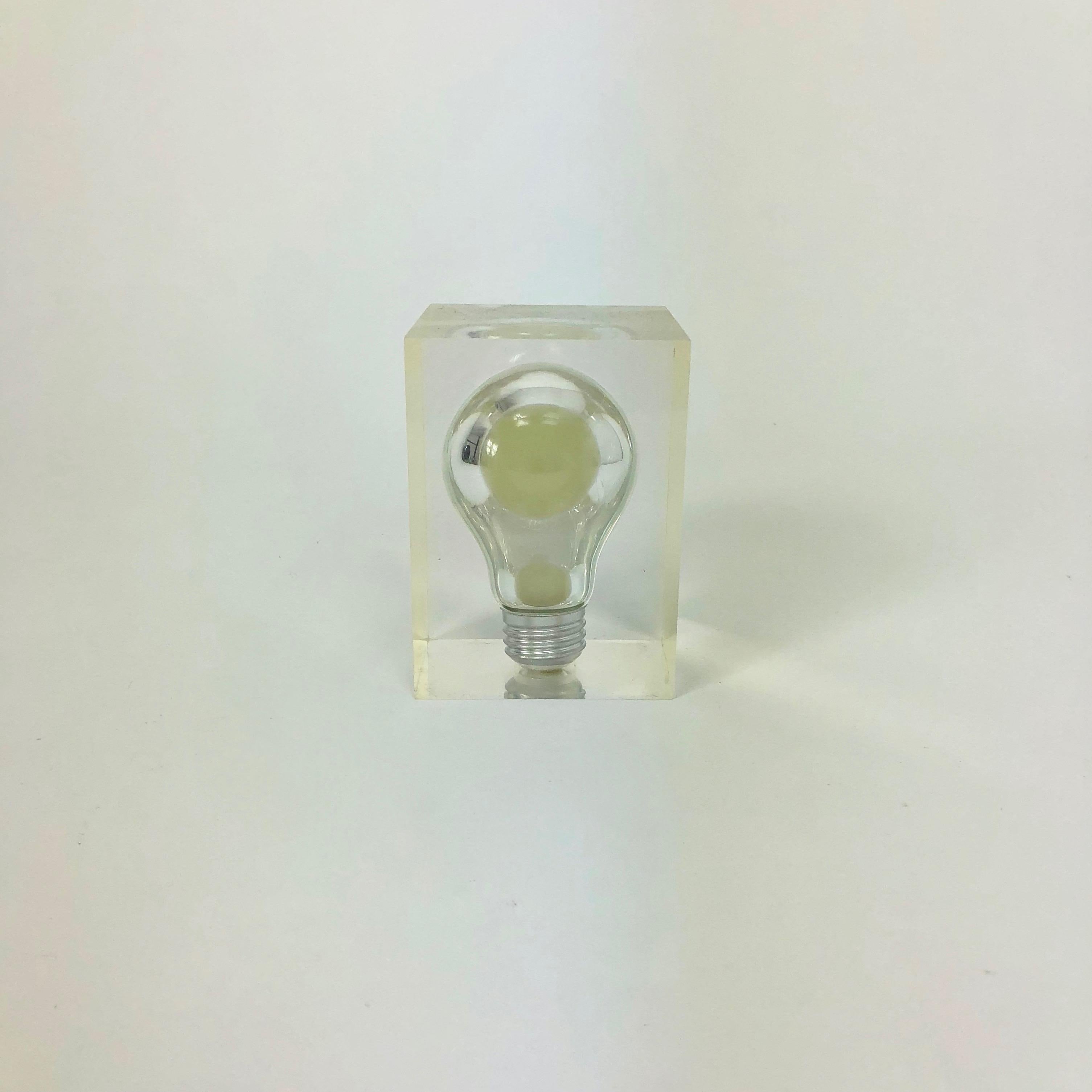 This small but amazing French Pierre Giraudon haunting pop art Lucite light bulb sculpture glows in the dark. It lights up green inside in the dark and has the appearance of a light bulb floating in mid air. The phosphorescent bulb is encased in