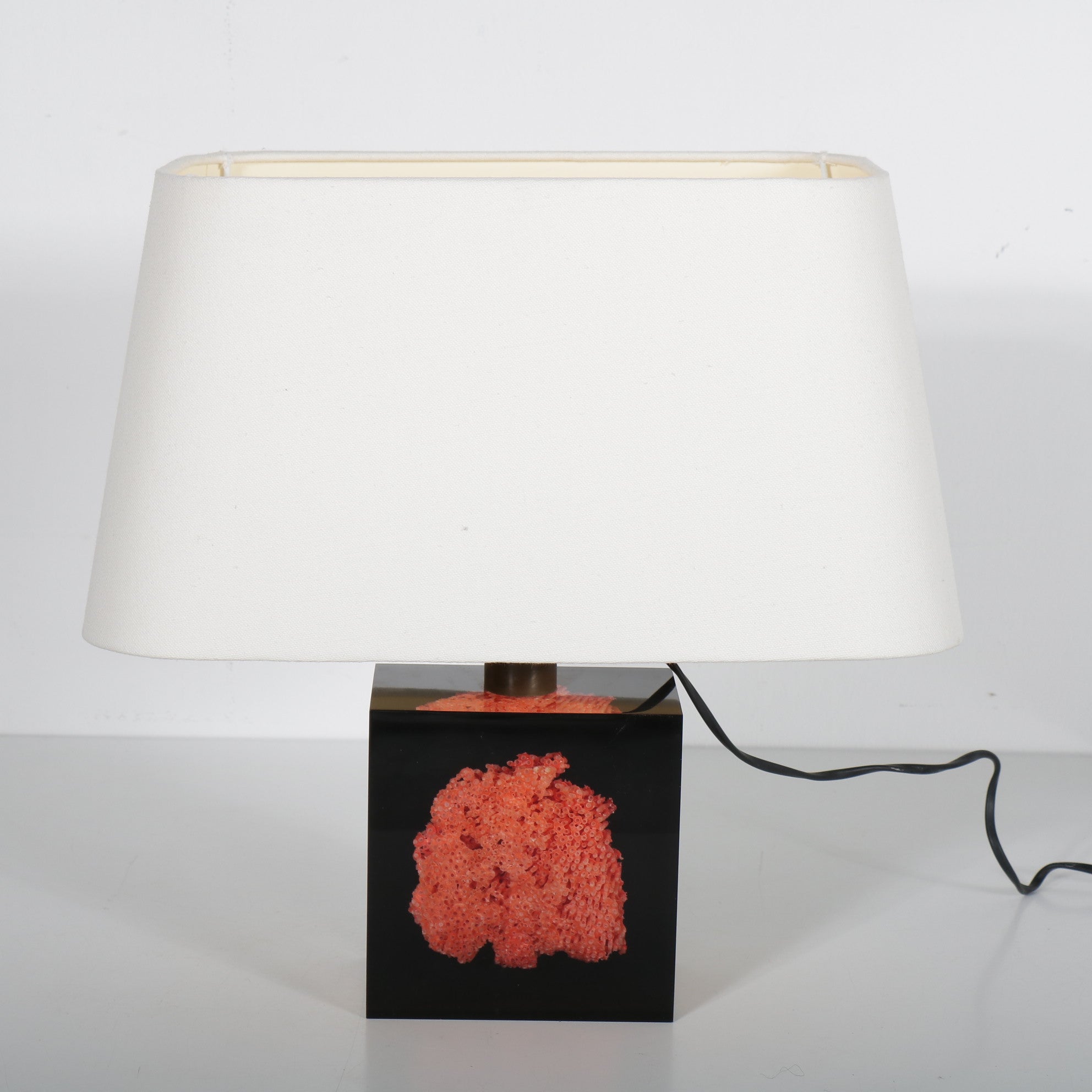 A luxurious table lamp by French designer Pierre Giraudon, manufactured in France around 1970.

The eye-catching feature of this piece is that it has a square clear resin base which holds a red / orange piece of coral. The back of the cube is made