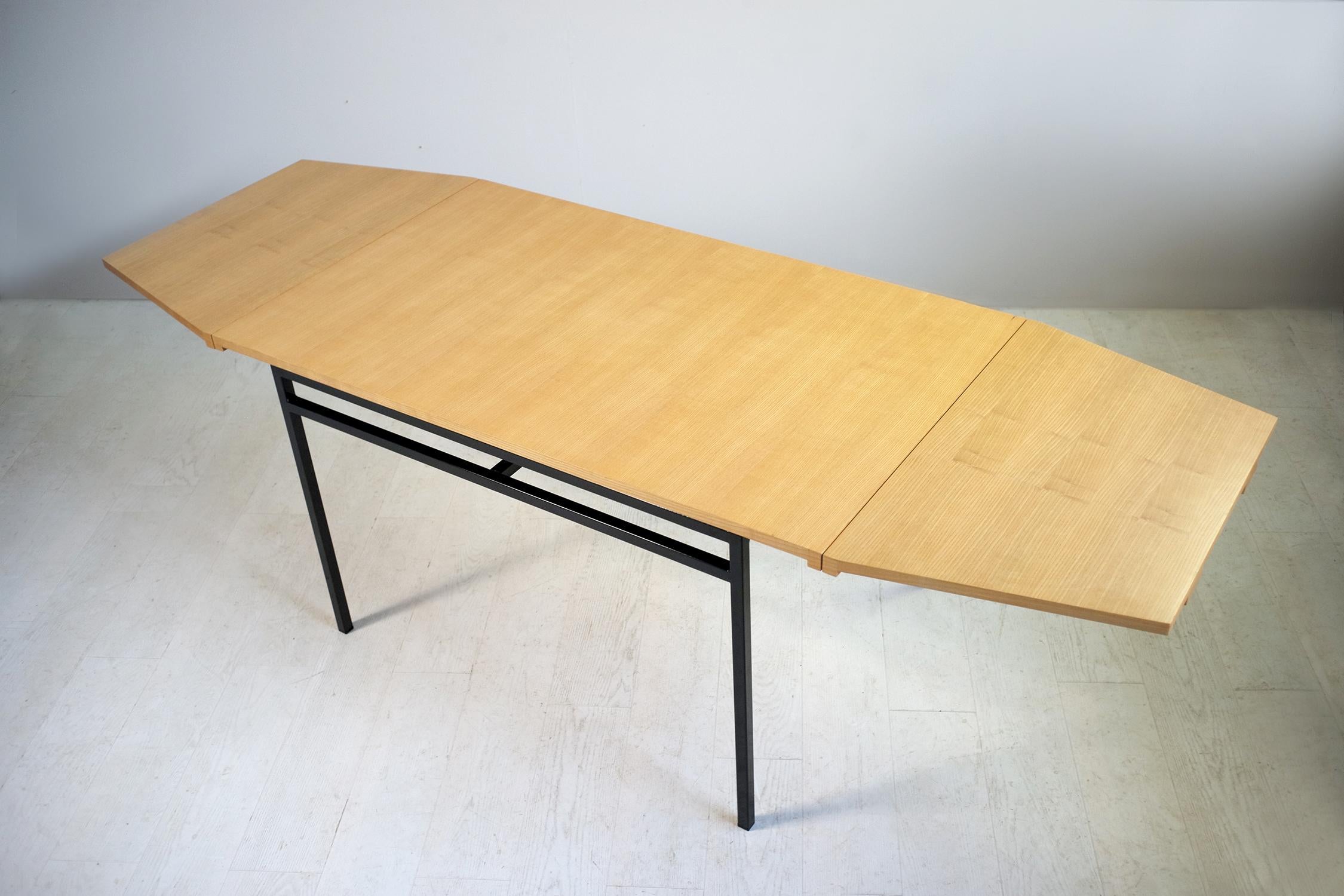 Pierre Guariche and the Atelier de Recherches Plastiques for the Huchers Minvielle, France, 1955; Dining table with rectangular top in golden ash, with two trapezoidal extensions, black lacquered quadrangular metal base. Dimensions of the top 140/85