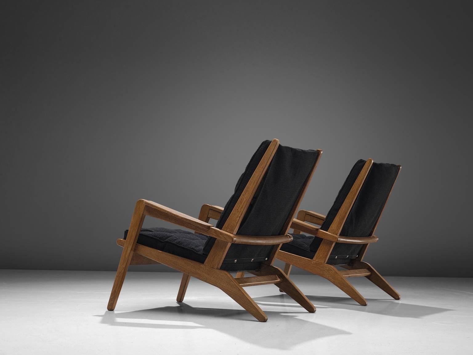 Pierre Guariche for Airborne, pair of lounge chairs model FS 105 model, solid oak, black fabric, France, 1940s.

These armchairs in solid oak are designed by Pierre Guariche for Airborne. The structure with spring system supports the two thick