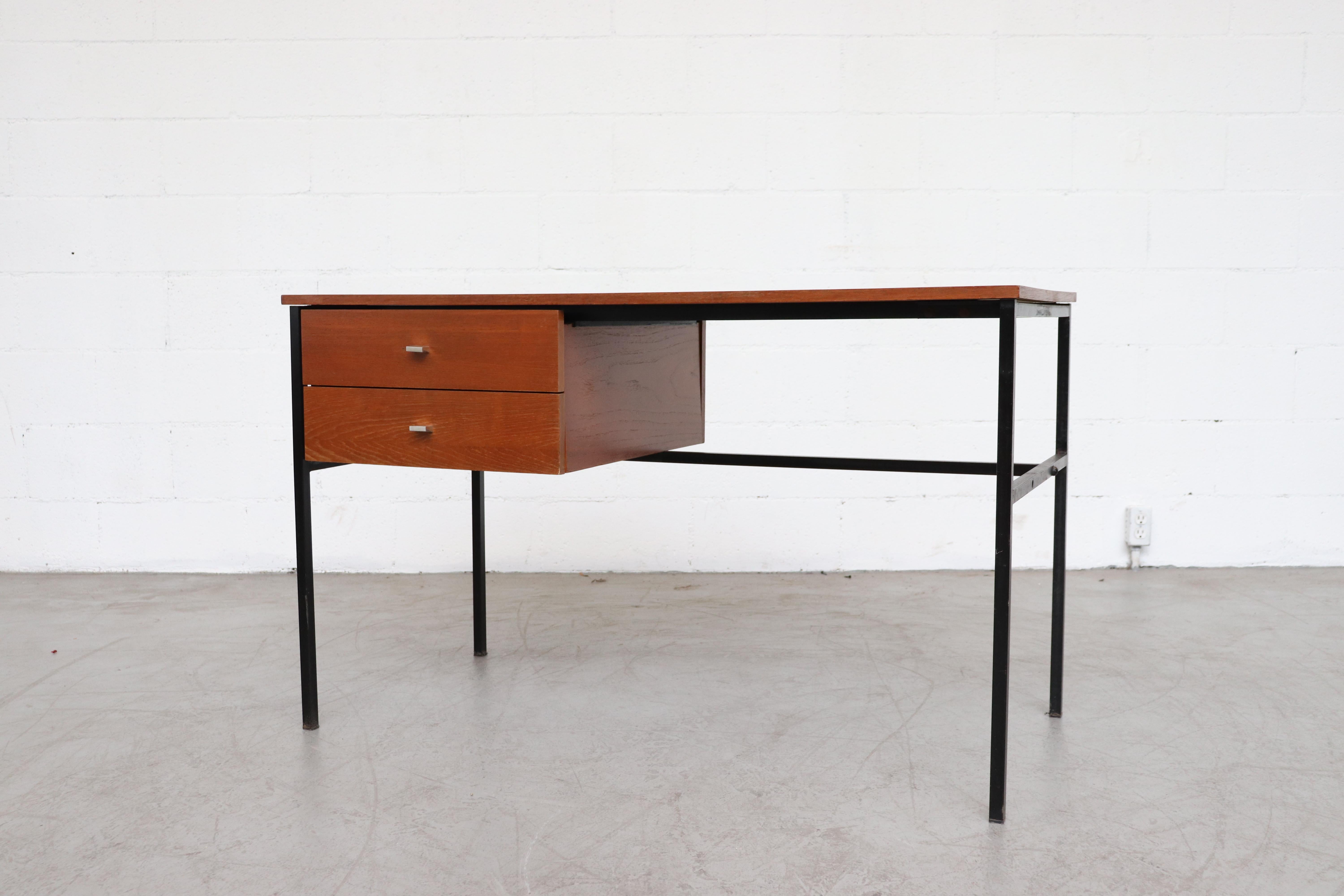 Pierre Guariche teak writing desk for Meurop with black metal frame and two drawers. Holes in frame are there to allow changing the drawer cabinet to the right side or left side. In original condition with some visual signs of wear consistent with