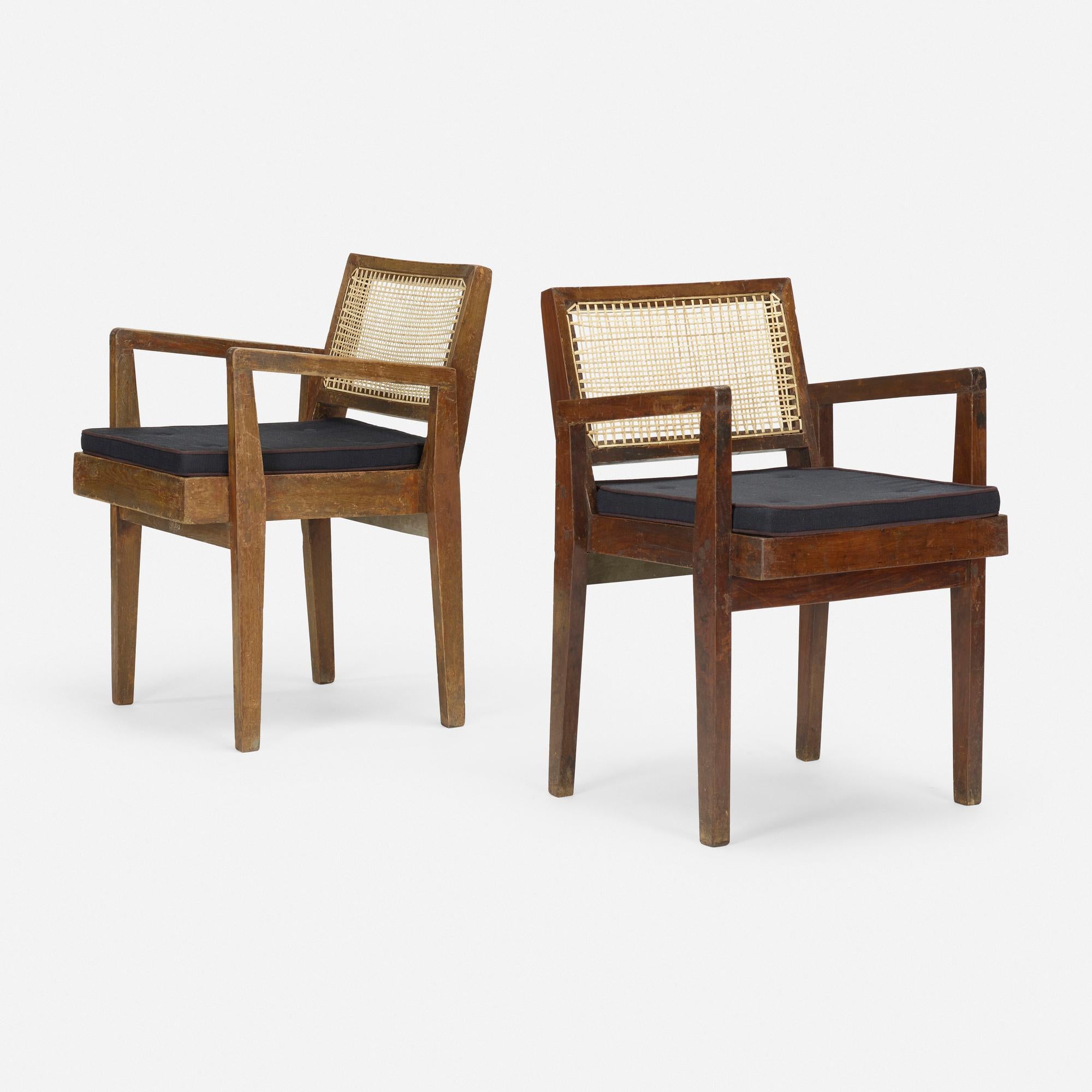 A pair of authentic arm chairs from Chandigarh deisgned by Pierre Jeanneret. Date of manufacture is between 1955-1960. These chairs are made of solid Burma teak with caned seats and backs.  The rear upper rail of each chair base has been stenciled.