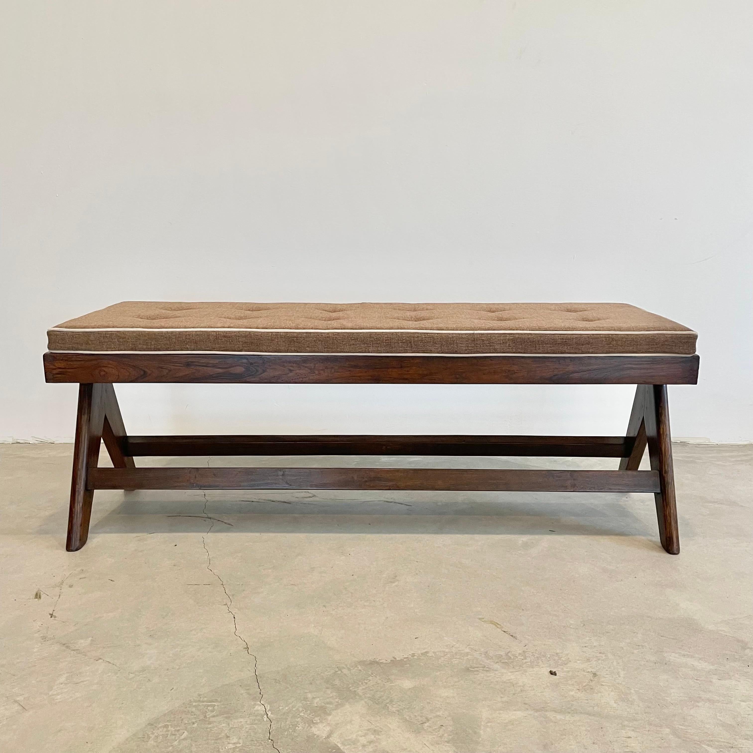 Stunning solid teak bench designed by Pierre Jeanneret for Chandigargh. Stencil reads - M.L.A.(GH)-036. Rectangular seat resting on two compass type side legs. Connected by a crossbar connecting each leg to its opposite. New caning. New cushion.