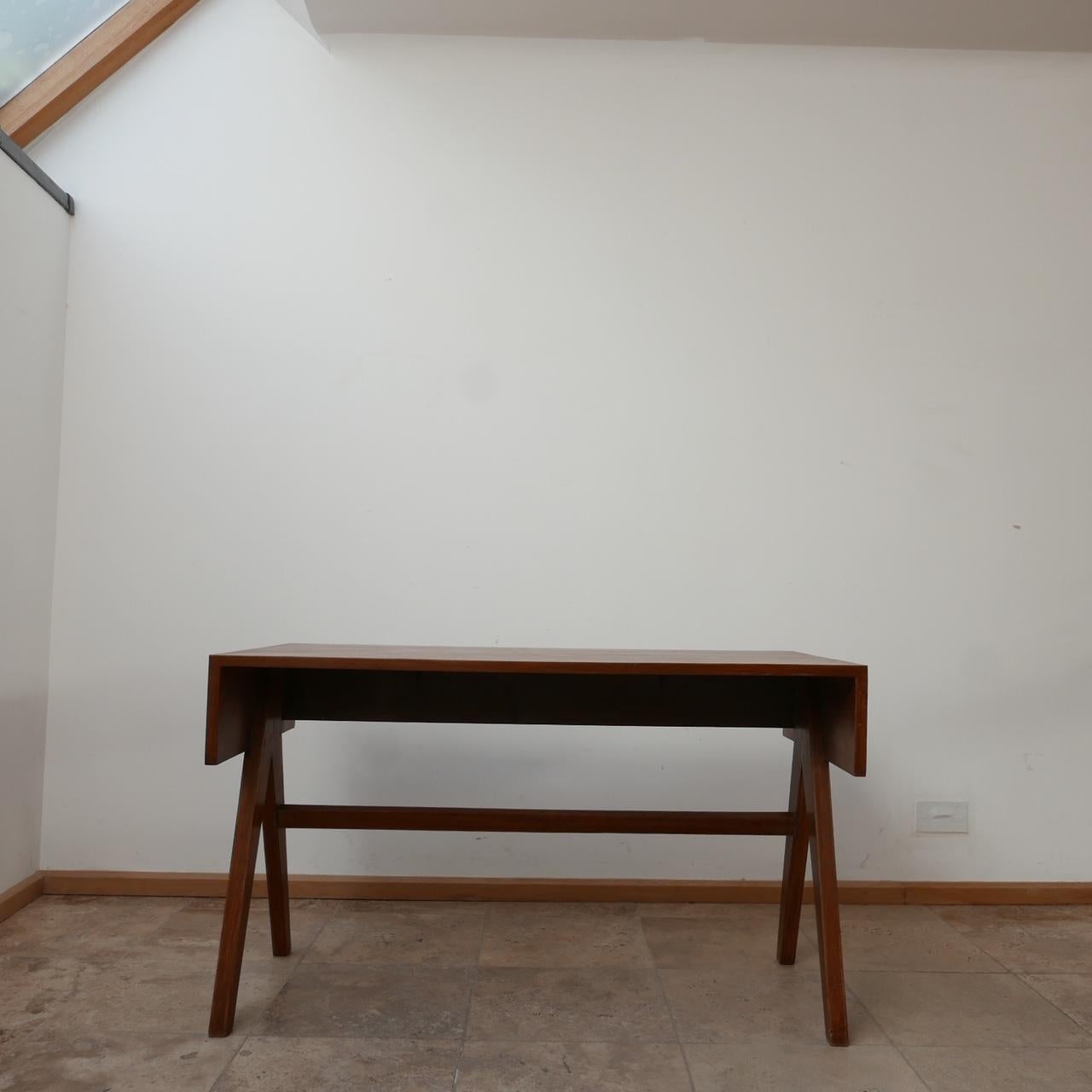 A scarce 'student' desk by Pierre Jeanneret. 

Formed from teak. 

India, c1960s. 

Compass style legs, the desk remains in good vintage condition. 

Location: London Gallery. 

Dimensions: 122 W x 61 D x 771.5 H in cm.

Delivery: