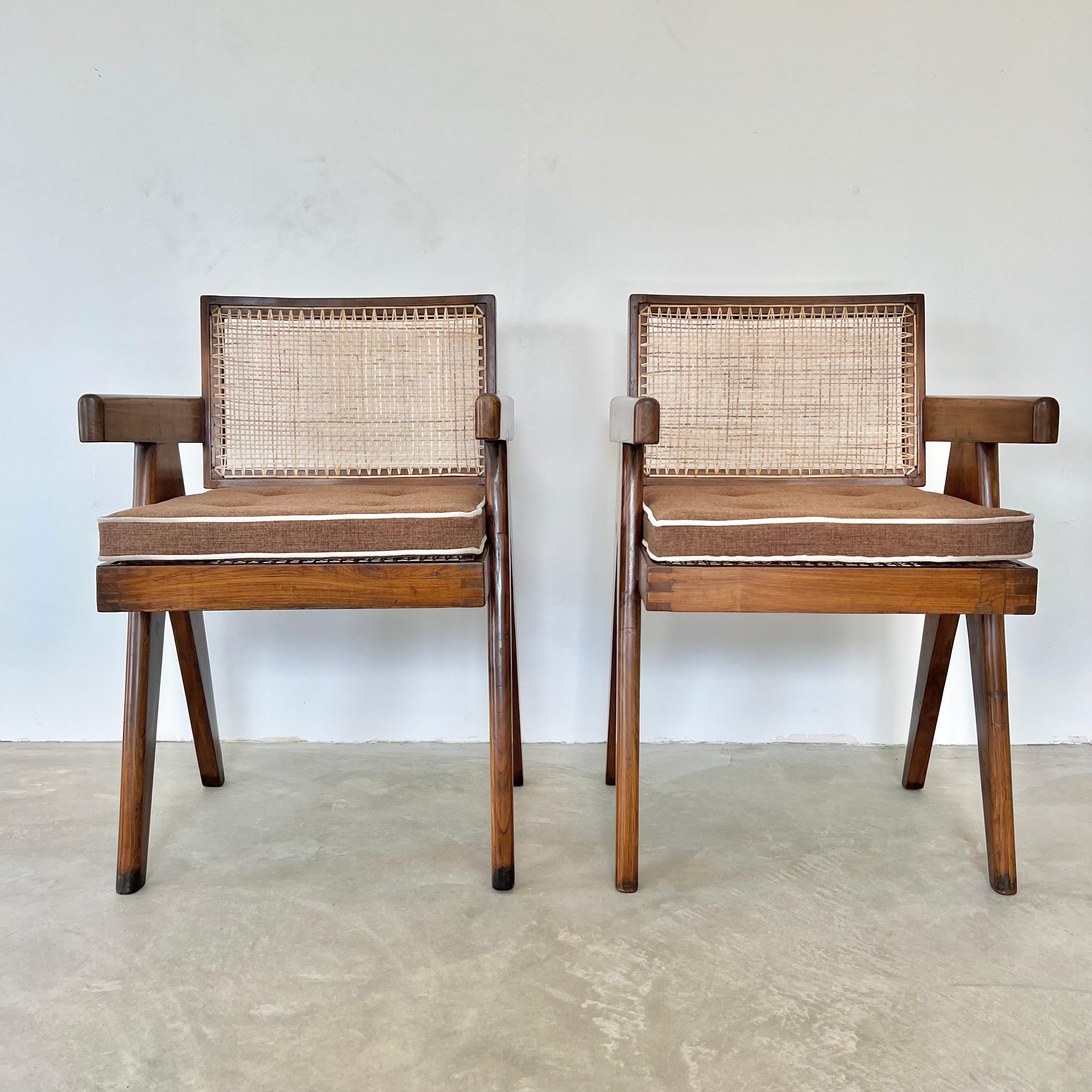 Fantastic collection of Pierre Jeanneret office chairs. Model PJ-0101-6S. Solid teak chairs with compass style legs, cane seat, and cane seat back. Slanted, slightly curved backrest. Hand stenciling on the back of both chairs reads : ASM, (L) -006