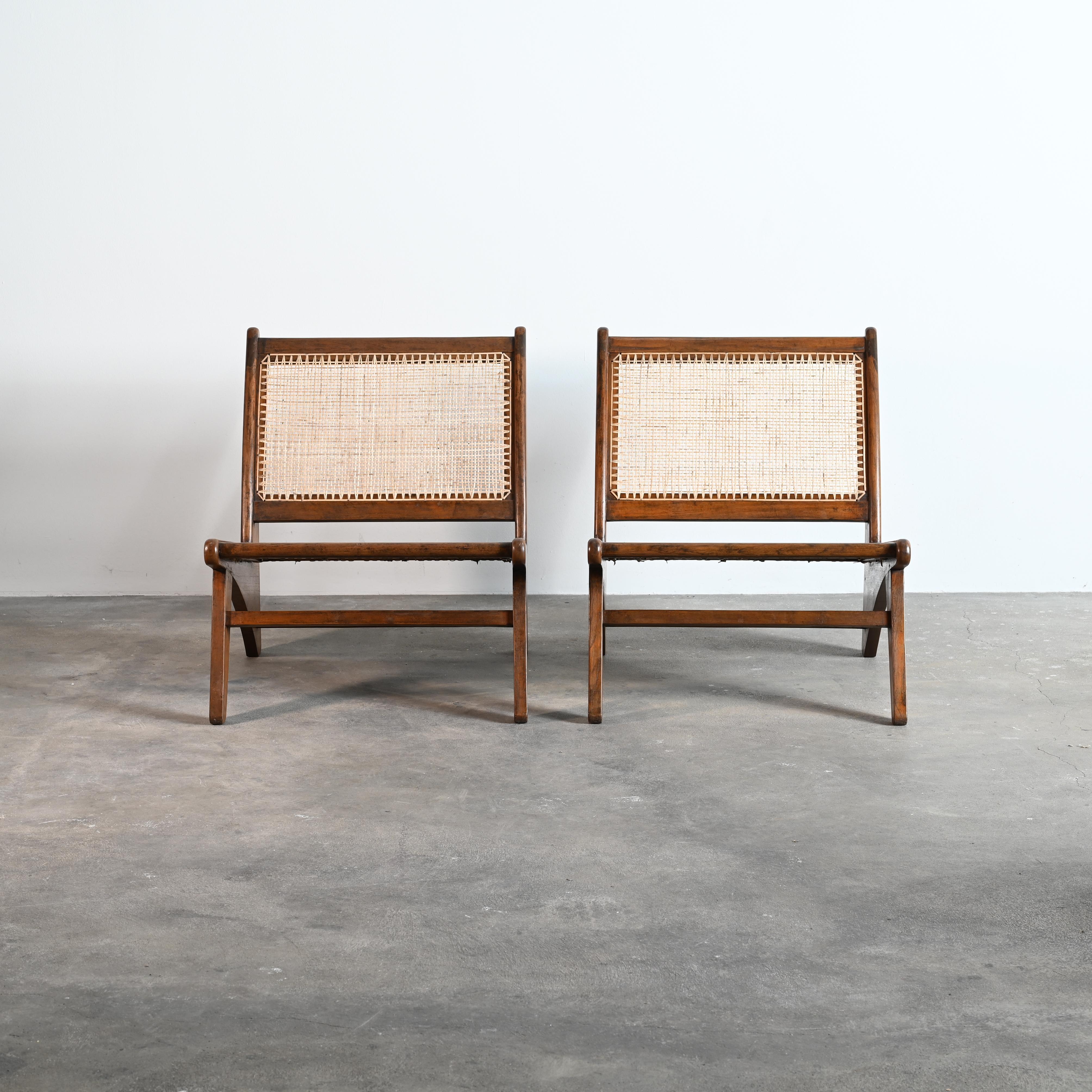 Pair of original and rare version of the easy chair by Pierre Jeanneret comes with a curved back leg and a front leg outside the continuation of the lateral frame. This feature adds to the exceptional appearance of this iconic object. Consisting of