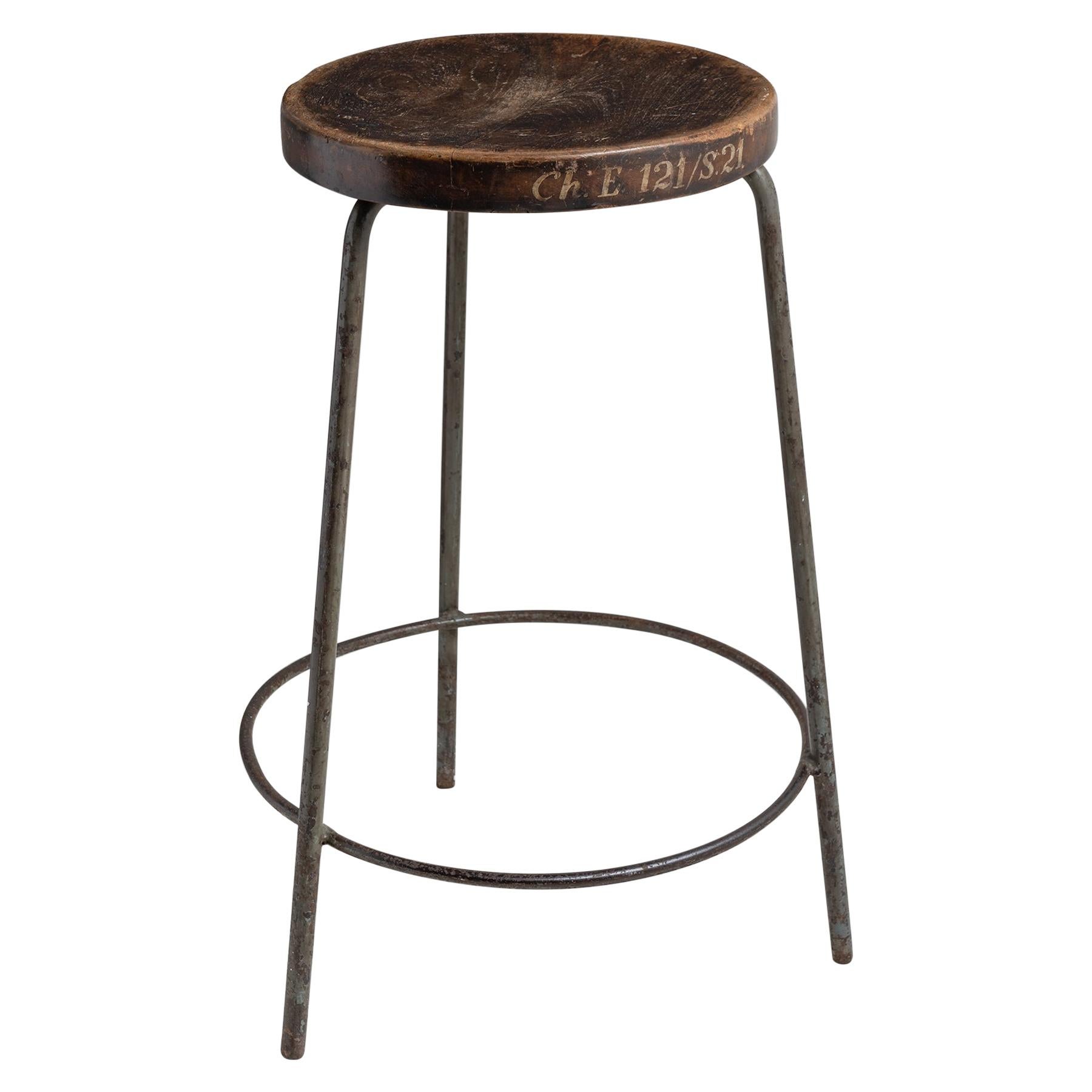Three-legged painted iron and teak stool from the School of Chemical engineering. With concave seat, all in original finish. Hand painted with classroom and seat number.