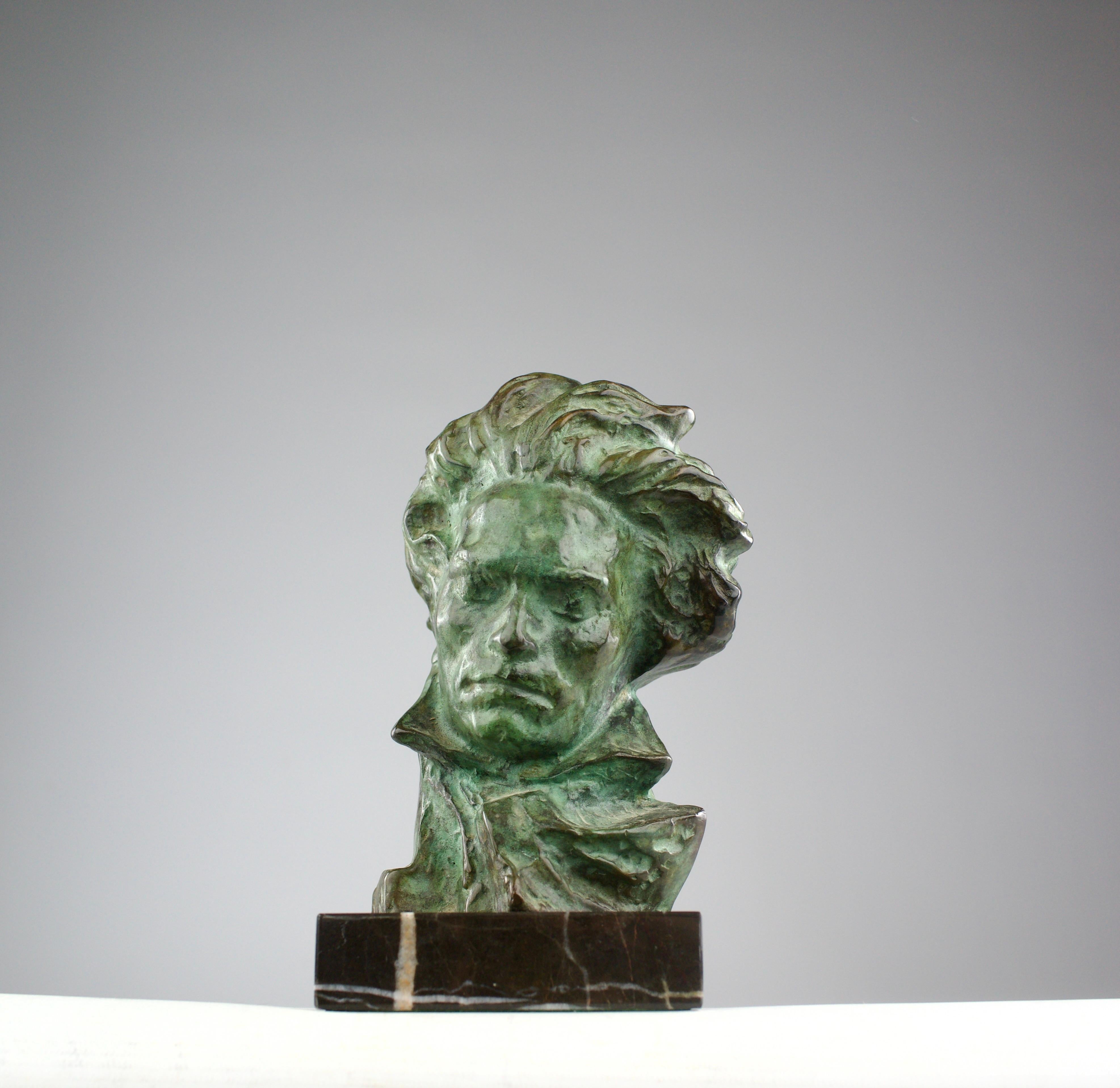 A stunning green-patinated bust of Beethoven, sculpted by Pierre Le Faguays for Max Le Verrier, rests gracefully upon a black, white-veined marble base. A masterpiece of French Art Deco from the 1920s, it captures the composer lost in the spell of