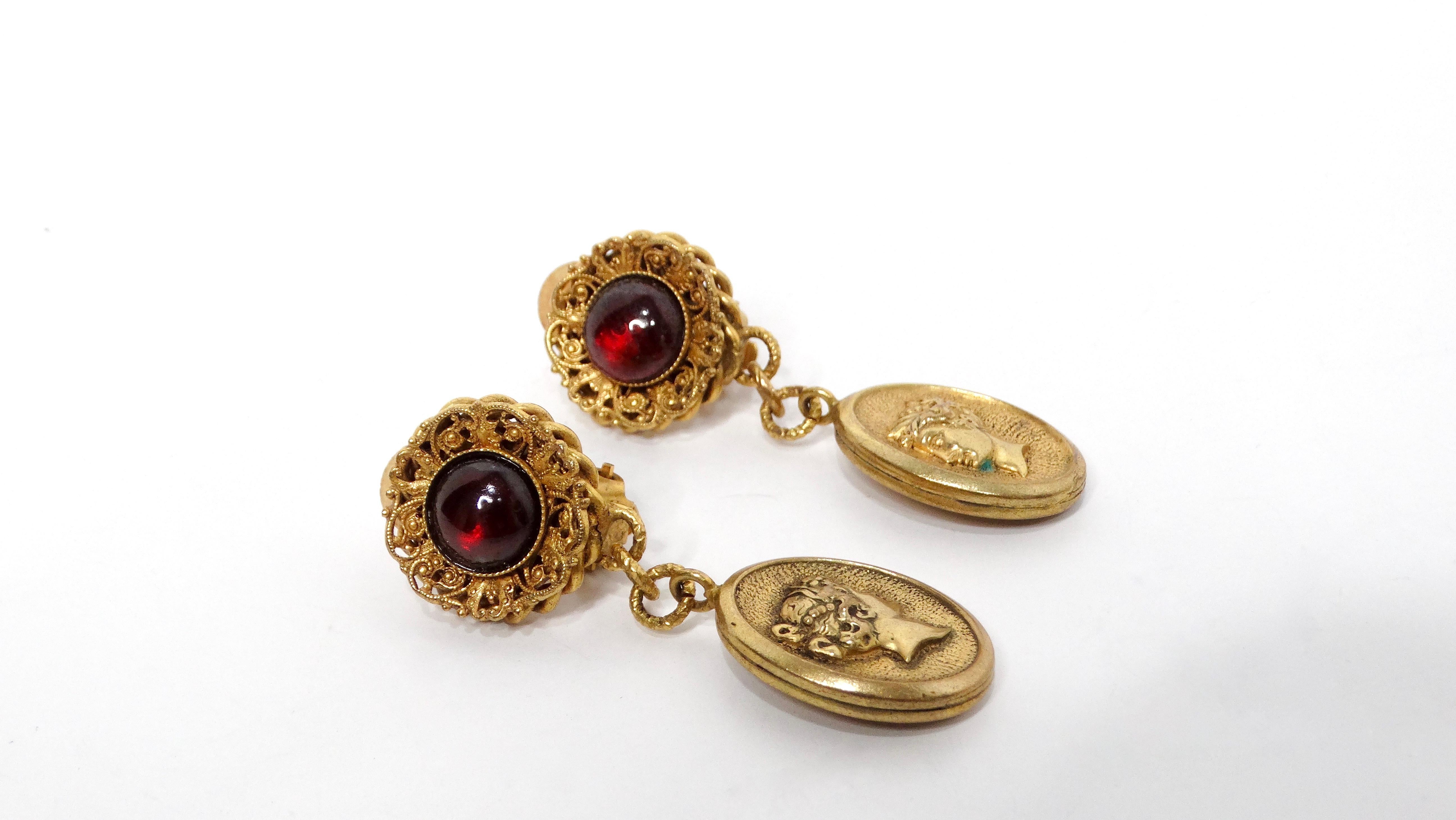 Ces boucles d'oreilles pendantes médaillon en ton or des années 1980, ornées de cabochons rouges captivants, apportent une touche de charme vintage. Le design Eleg présente un cabochon en verre au sommet, serti dans un cadre extérieur magnifiquement