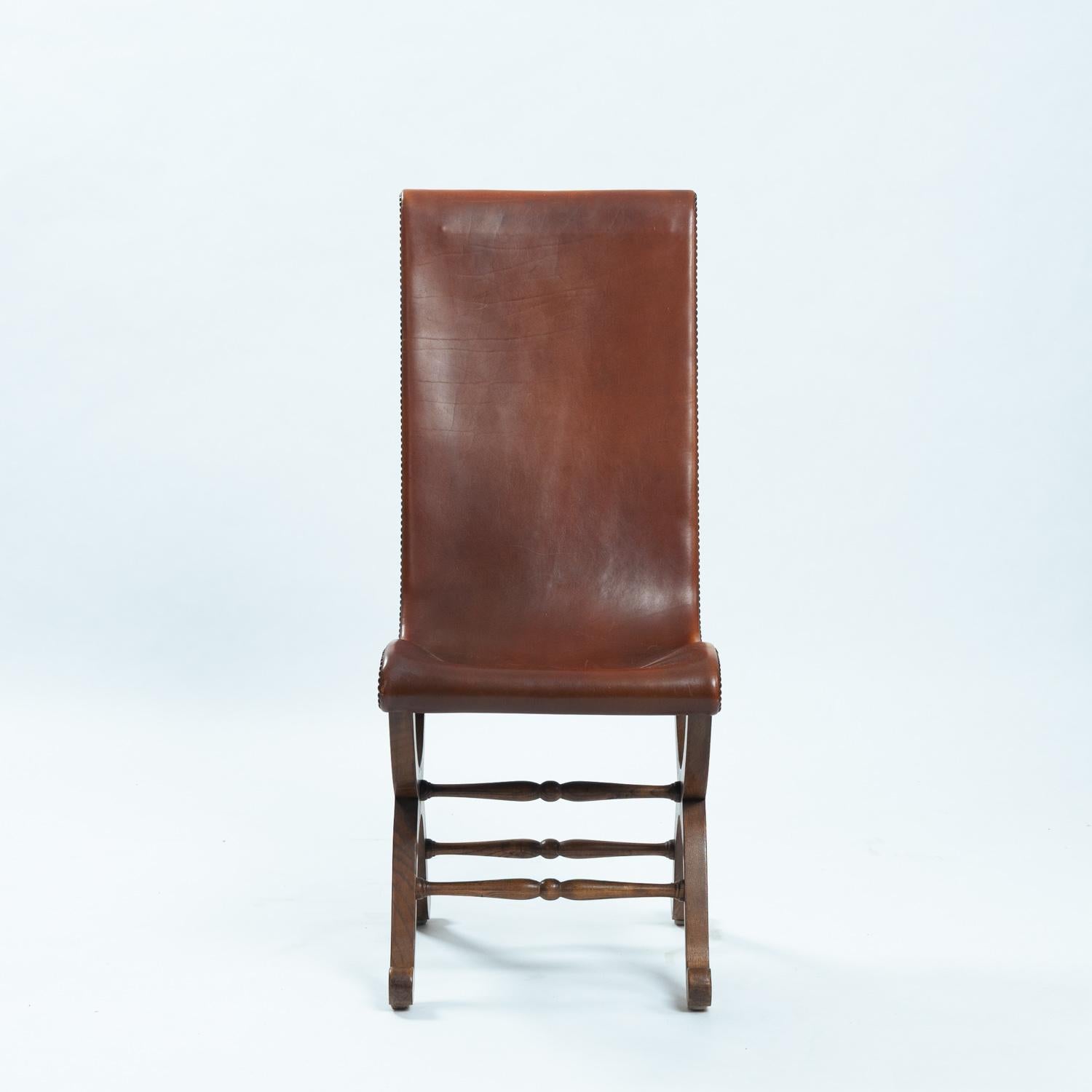 Silla auxiliar neoclásica española de respaldo alto diseñada por Pierre Lottier para Almazan, años 50. 
Estructura de madera de roble de líneas curvas y armoniosas donde descansa el respaldo de cuero marrón rojizo con tachuelas metálicas. 
En la