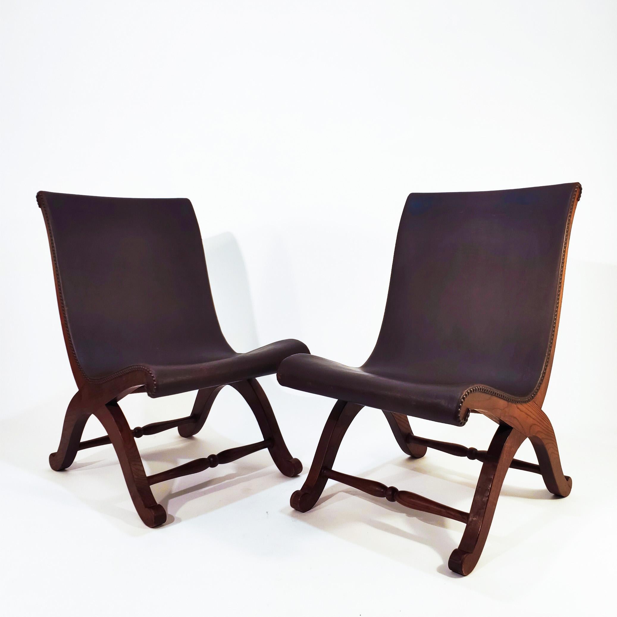Pair of Spanish slipper chairs designed by Pierre Lottier for Valmazan, 1940s. Oak wood structure with curved and harmonious lines where the dark chocolate brown leather backrest sits through brass studs. This chair became very popular in Spain in
