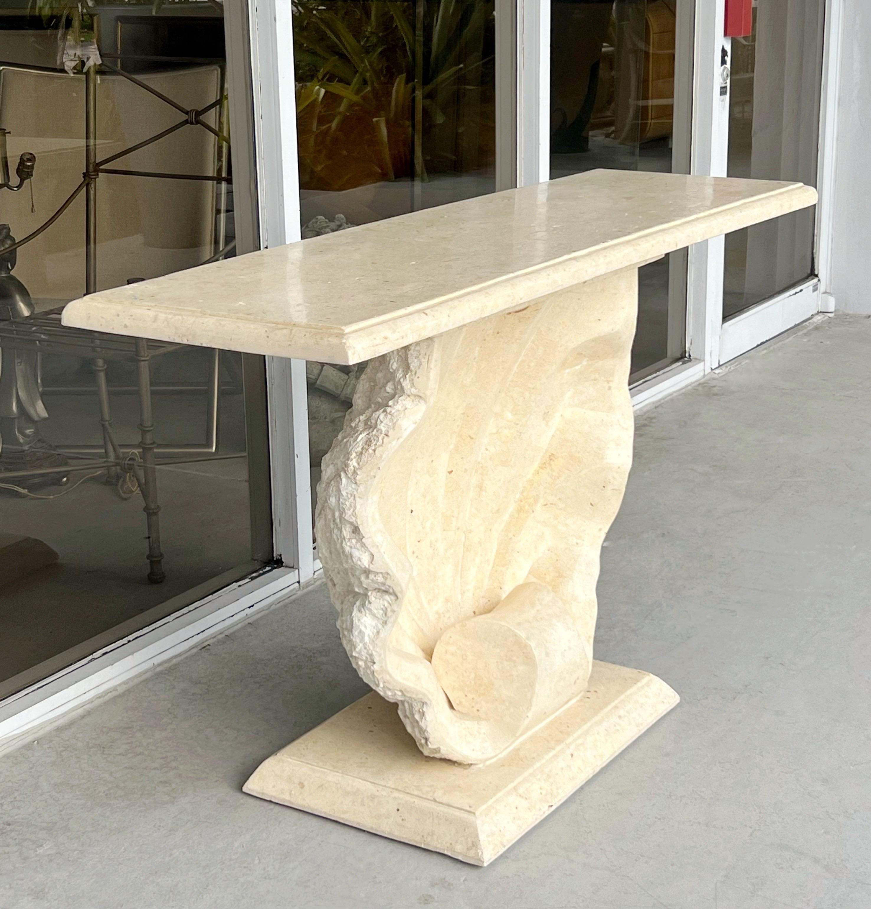 A carved fossil stone console table. Classic design with a large shell holding the top. The console is finished on all sides with the back of the shell done in a thick crusty manner while the rest of the console is polished. 