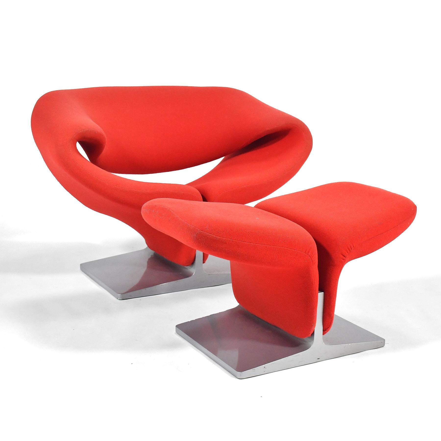 A sensuous design of sublime simplicity, the ribbon chair by Pierre Paulin is as comfortable as it is beautiful. This beautiful example by Artifort is upholstered in red fabric and comes complete with a matching ottoman, both pieces sport silver