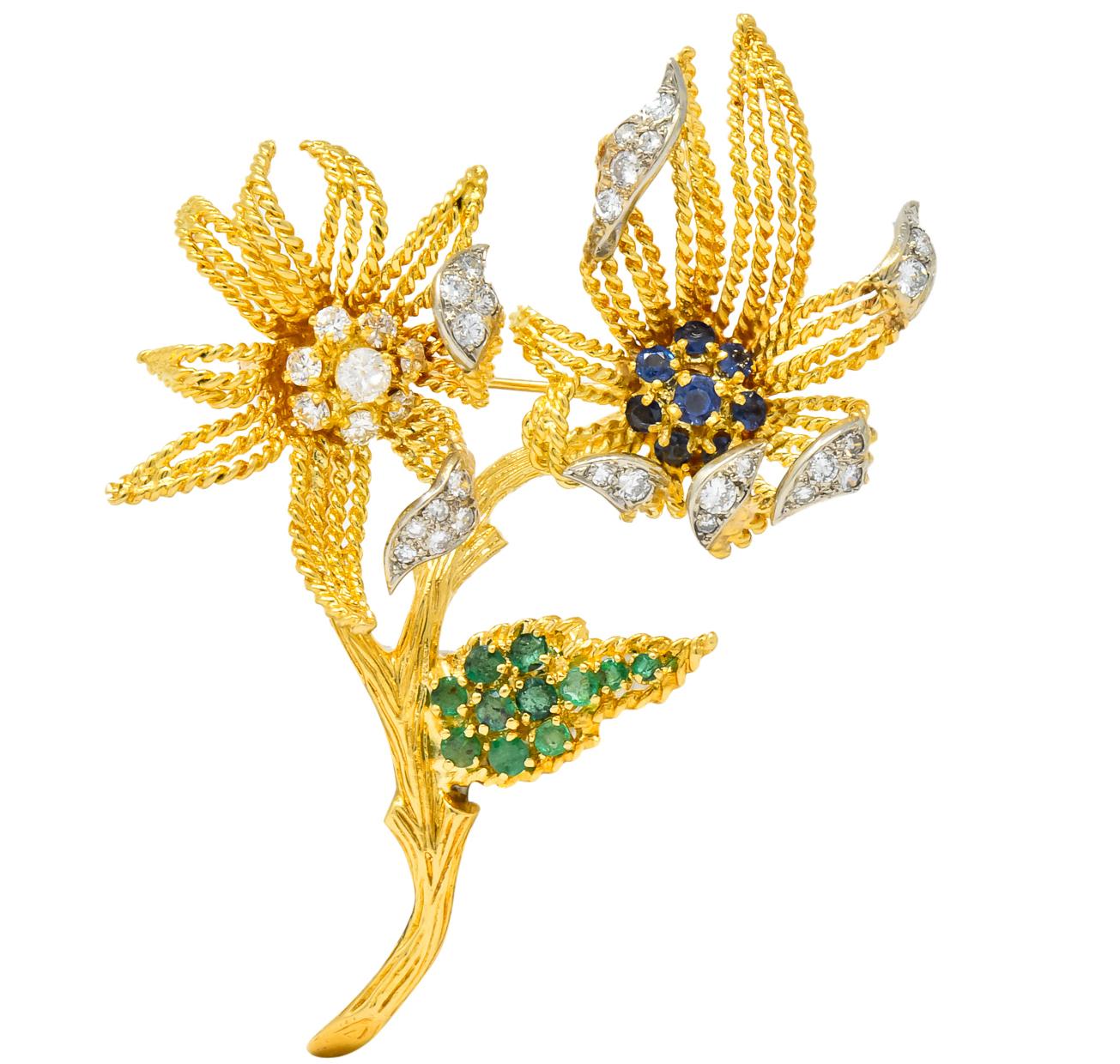 With twisted gold wire flowers petals and leaves and textured gold stem 

One centering round cut sapphires weighing approximately 0.70 carat, bright deep blue and very well matched

Leaf set with round cut emeralds, weighing approximately 0.70