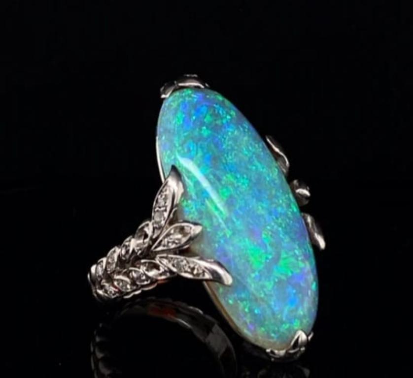 Anillo de cóctel Pierre Sterlé de ópalo y diamantes en platino, hacia 1950.

Este impresionante anillo está engastado en su centro con un excepcional cabujón de forma ovalada de 19,87 quilates aproximadamente, que está enmarcado por cinco elegantes