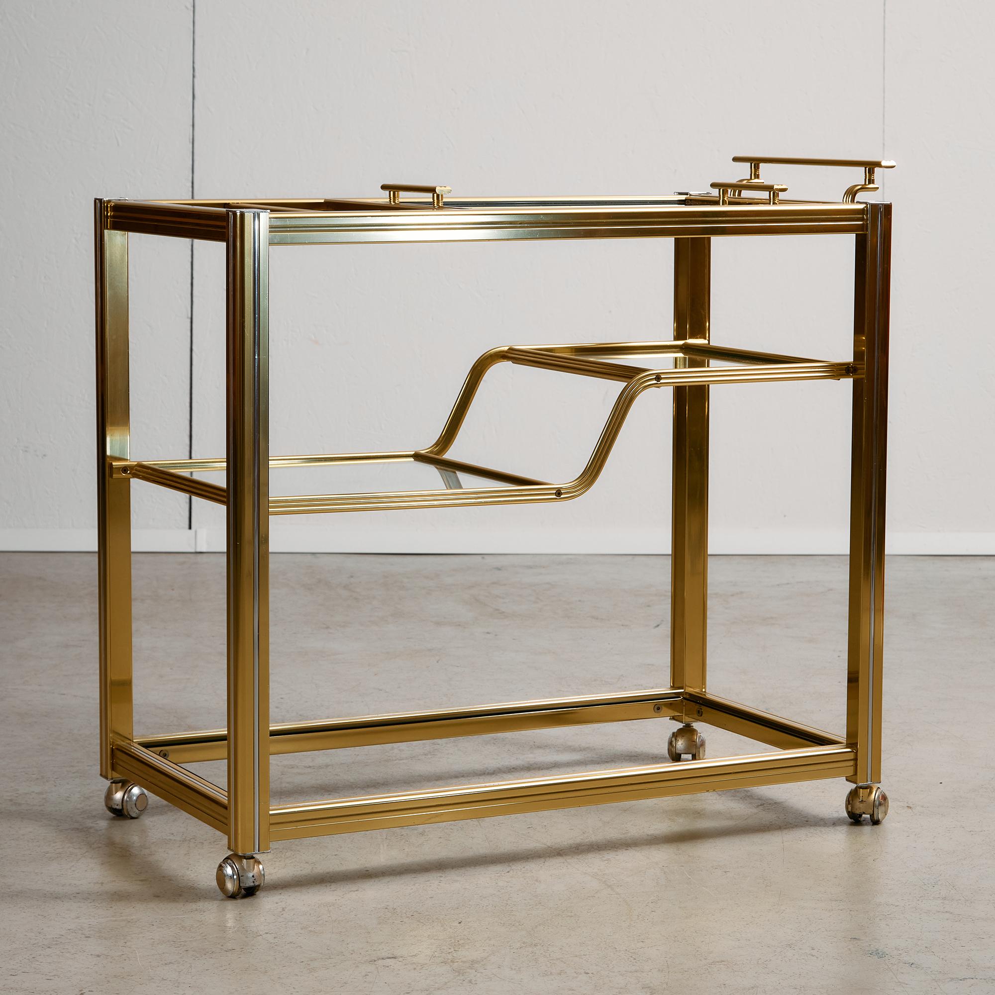 Este elegante carrito de bar de Pierre Vandel recoge el refinado espíritu del diseño francés de los años 70: líneas limpias, contrastes atrevidos y un pulido toque de glamour. El marco combina acabados dorados y cromados, lo que confiere a la pieza