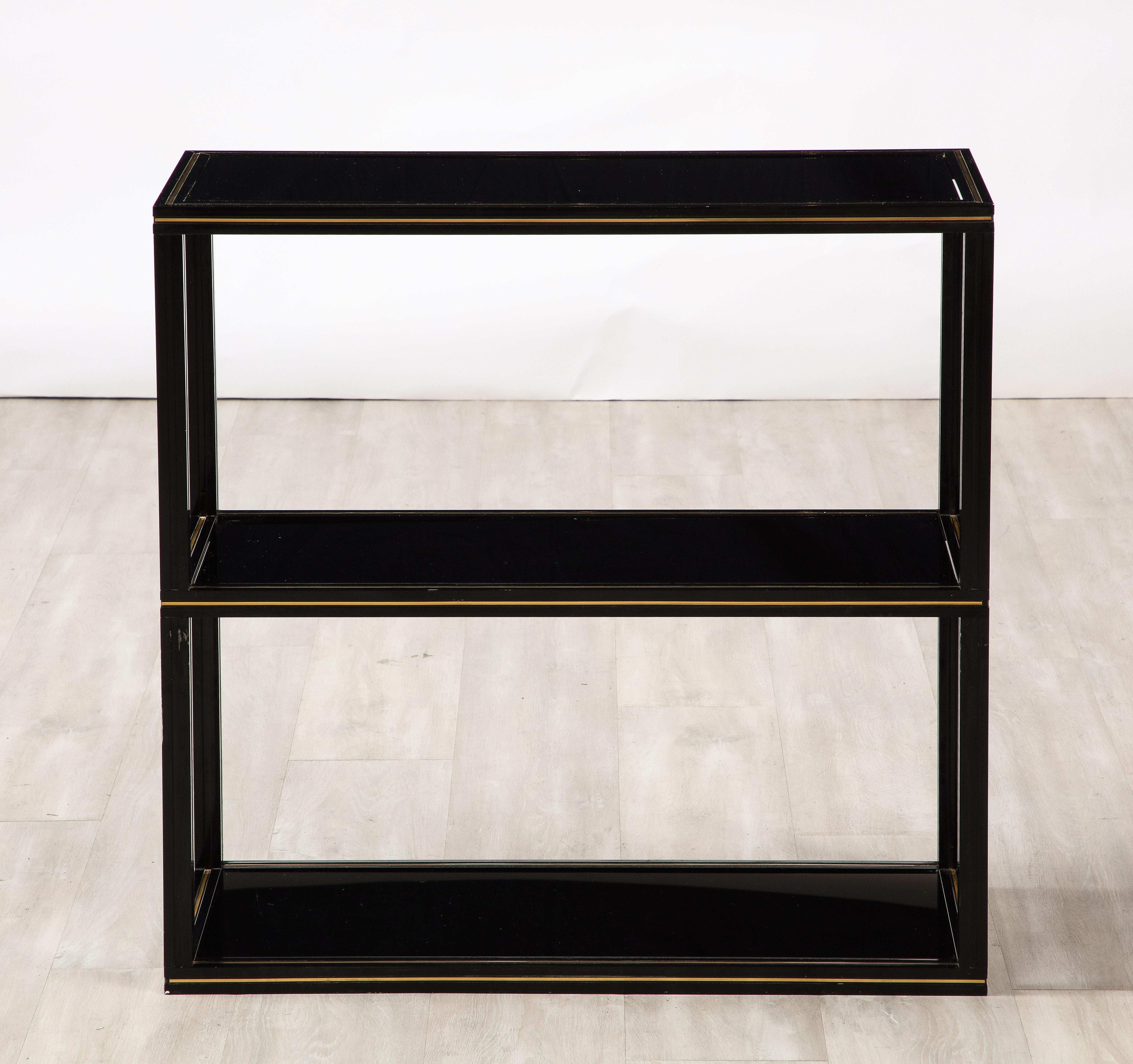 A Pierre Vandel black lacquered aluminum étagère with brass detailing and three black glass shelves. 
Labelled: Pierre Vandel
Paris, circa  1970
The cleanly defined lines of this shelving would be perfect for displaying studio pottery, books and