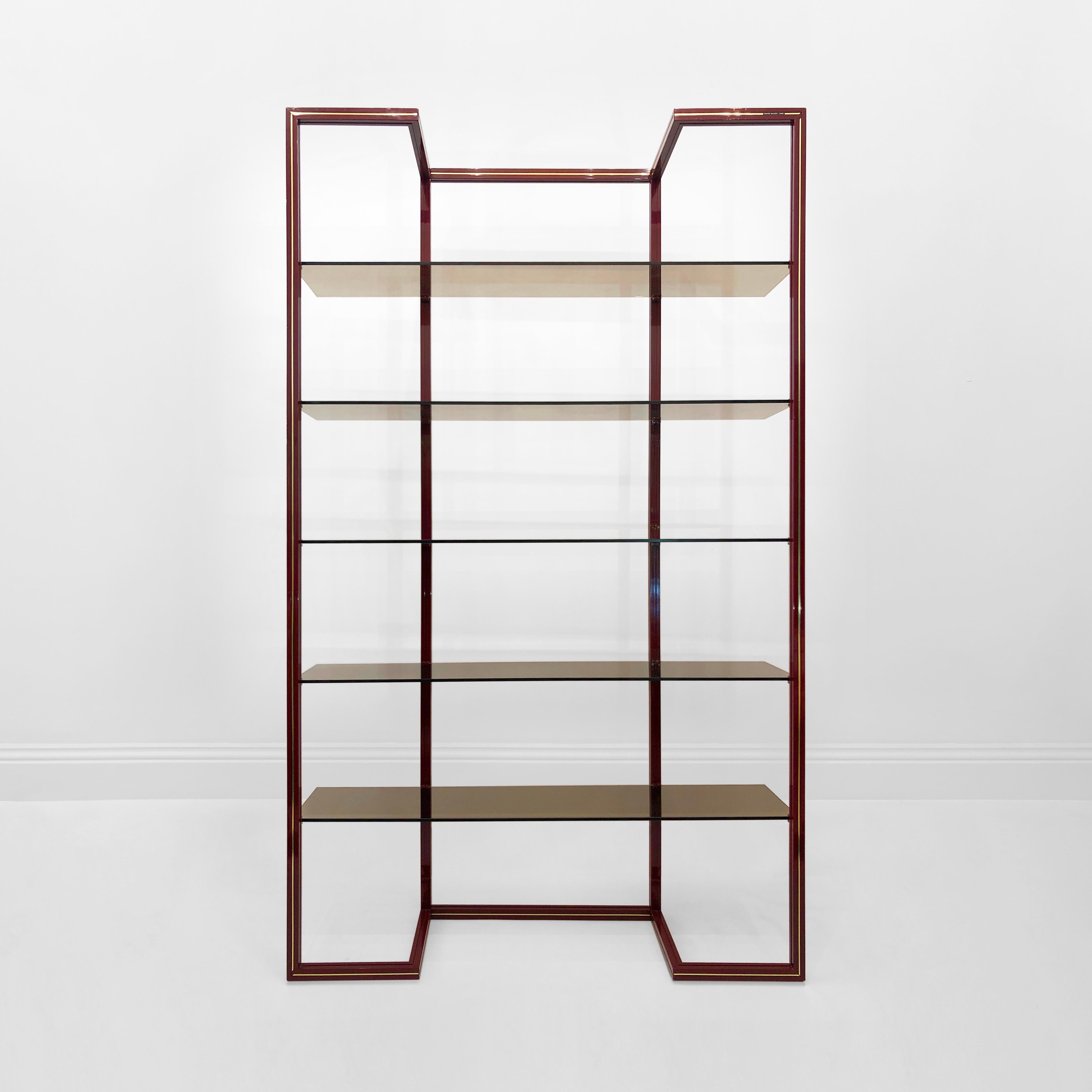 An étagère, in Pierre Vandel's inimitable style, with his idiosyncratic brass stripe down the centre of the deep burgundy powder-coated aluminium frame with a sort of a floating shelves illusion. The five smoked glass shelves complete this display