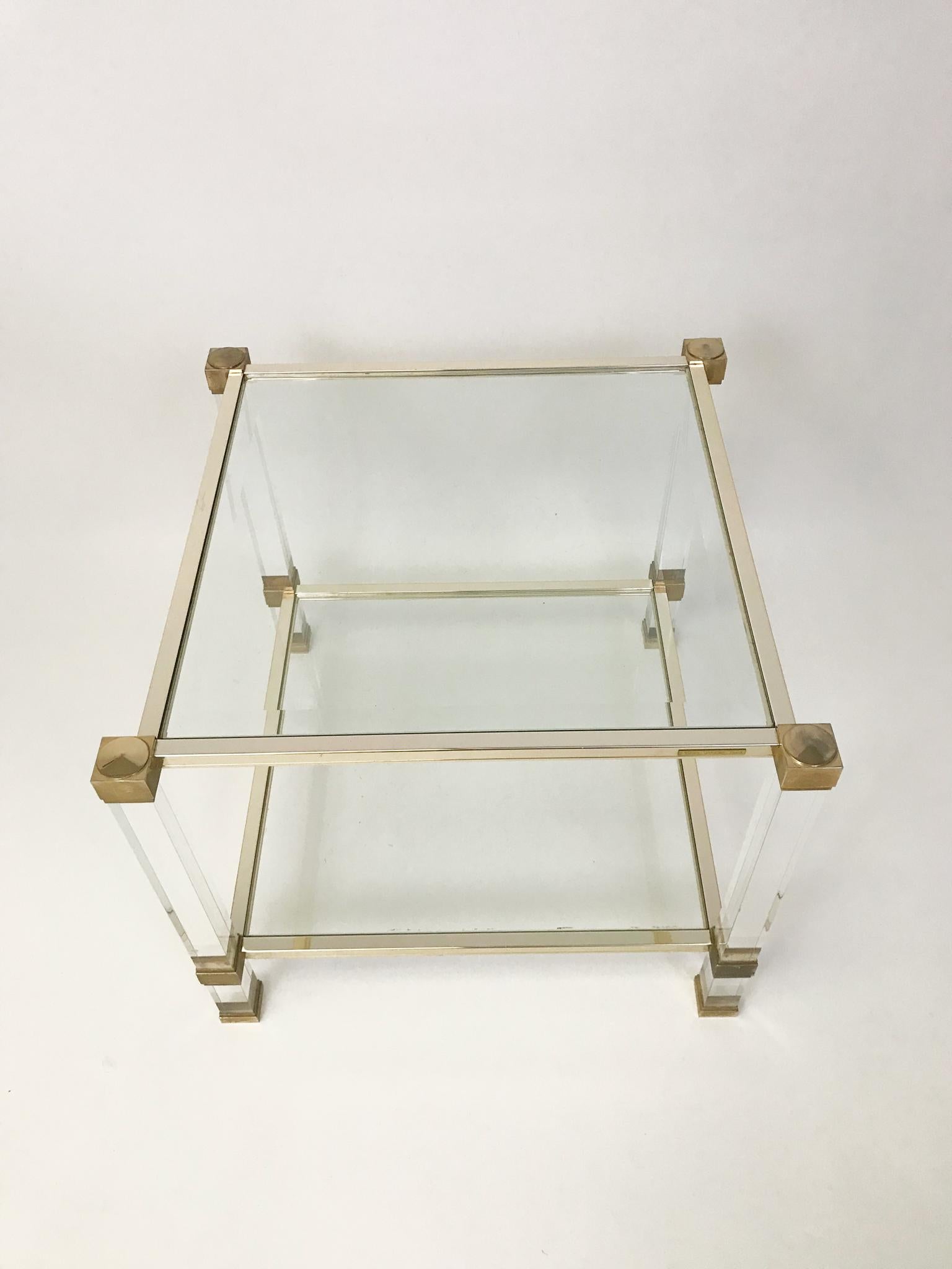 A Pierre Vandel square Lucite and brassed metal side table, with 2 tiers. Pierre Vandel label to top rail.

Height: 50cm
Width: 58cm x 58cm

Pierre Vandel was a French furniture company known for their luxury coffee tables, chairs, storage
