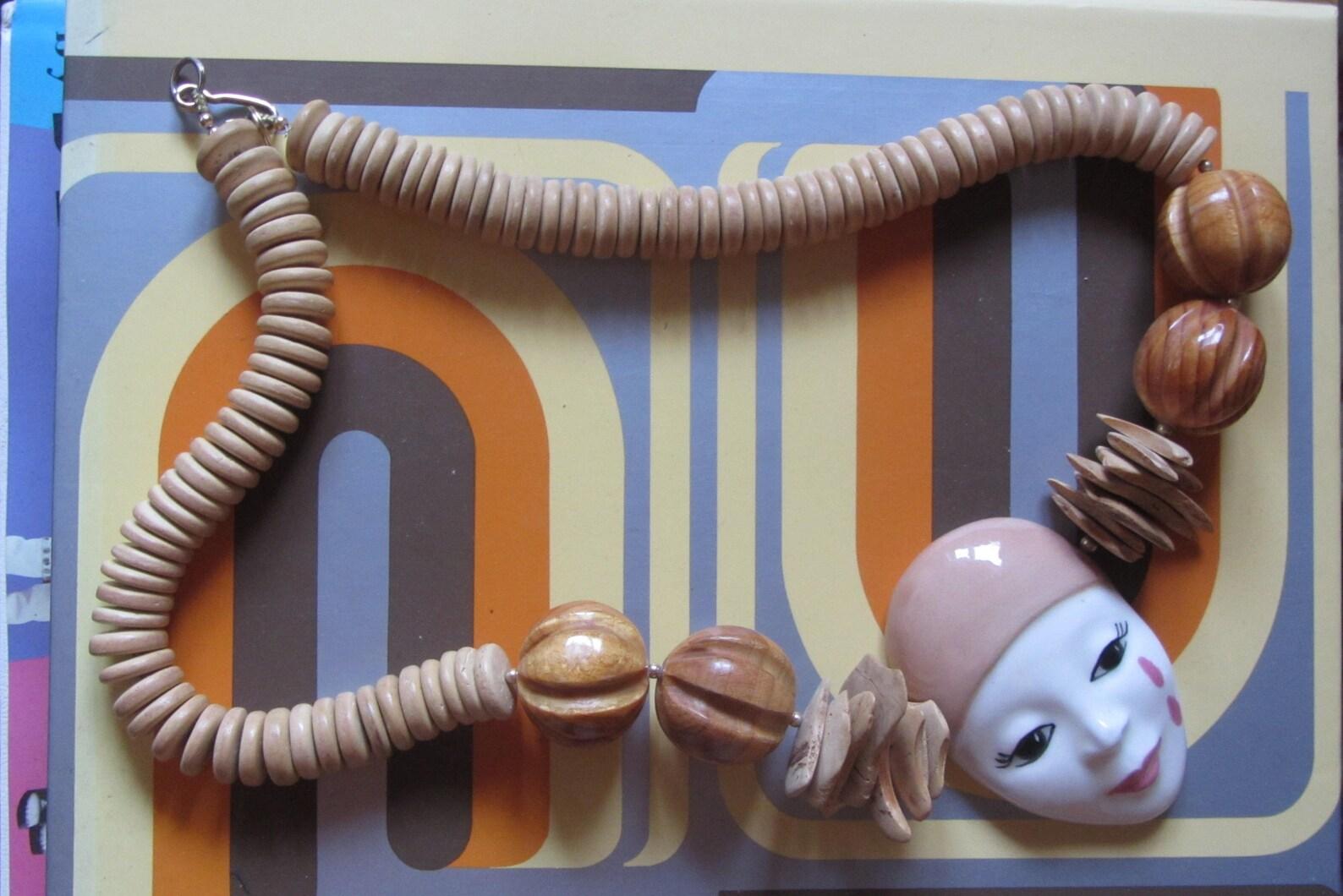 Una collana unica e meravigliosa! Ciondolo a forma di maschera di Pierrot dipinto a mano in porcellana/ceramica smaltata. Perline di legno e piccoli distanziatori dorati. La collana è infilata in un filo di metallo.

Marcature: Non firmato
Circa: