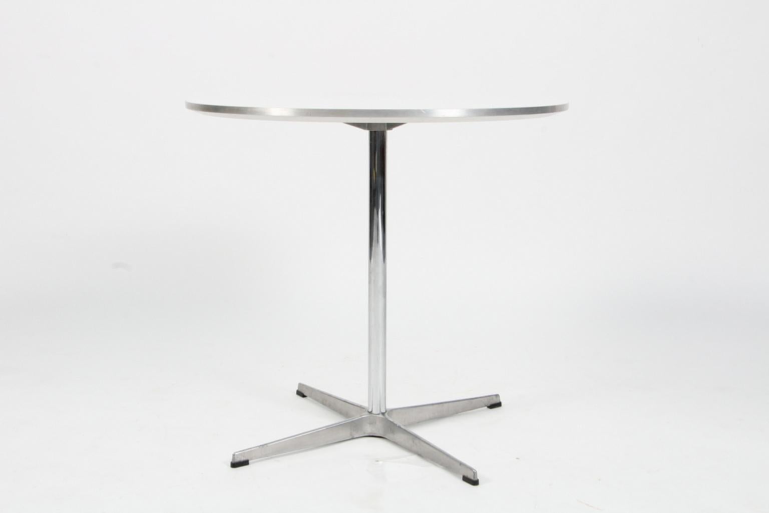 Piet Hein & Arne Jacobsen café table with white laminate and aluminium edge.

Four star base of aluminium and steel.

Made by Fritz Hansen 2007.