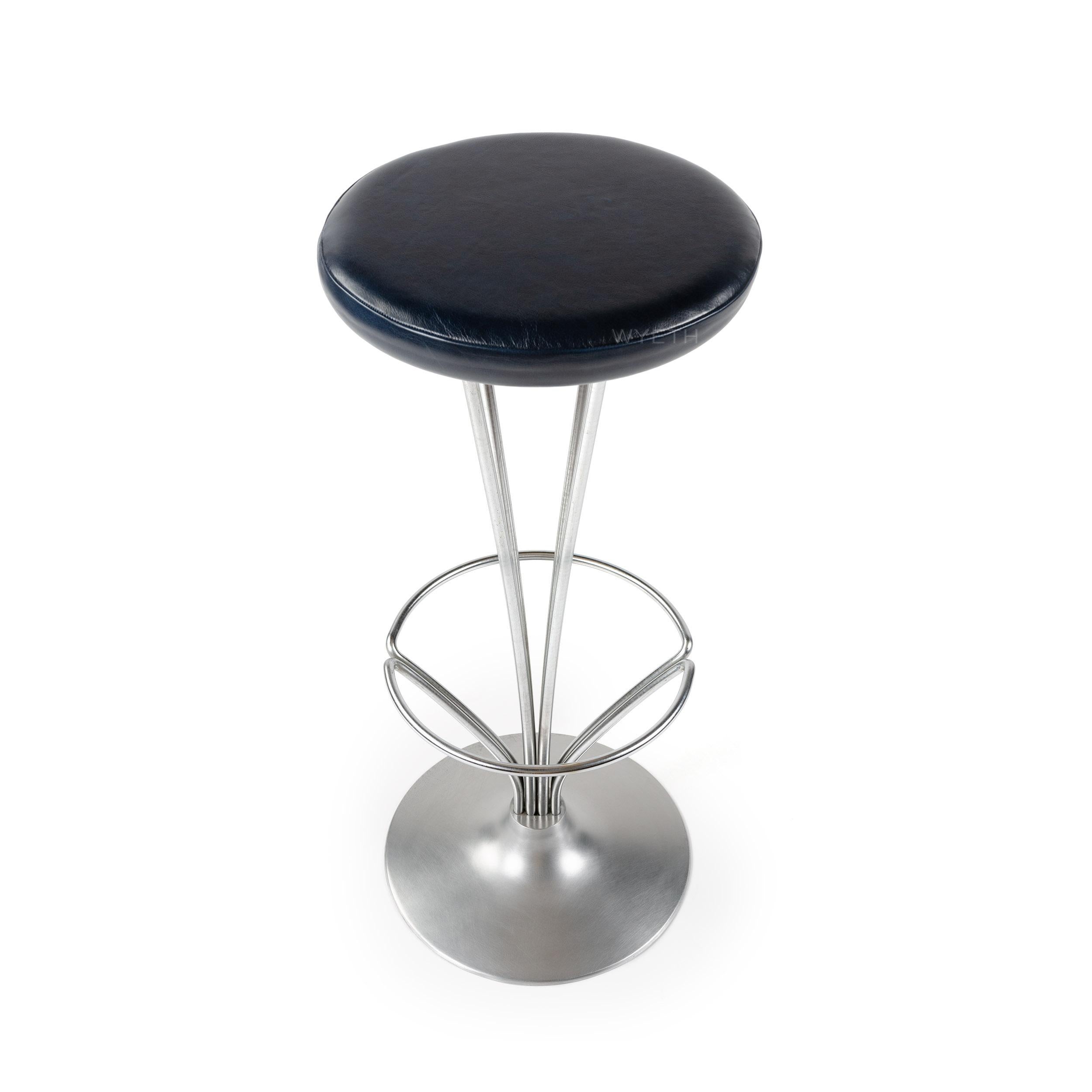A Scandinavian Modern pedestal style barstool with satin chromed steel bars - slightly arched to support a foot rest - and upholstered seat in dark blue leather. Designed by Piet Hein and manufactured by Fritz Hansen in the 1960s.