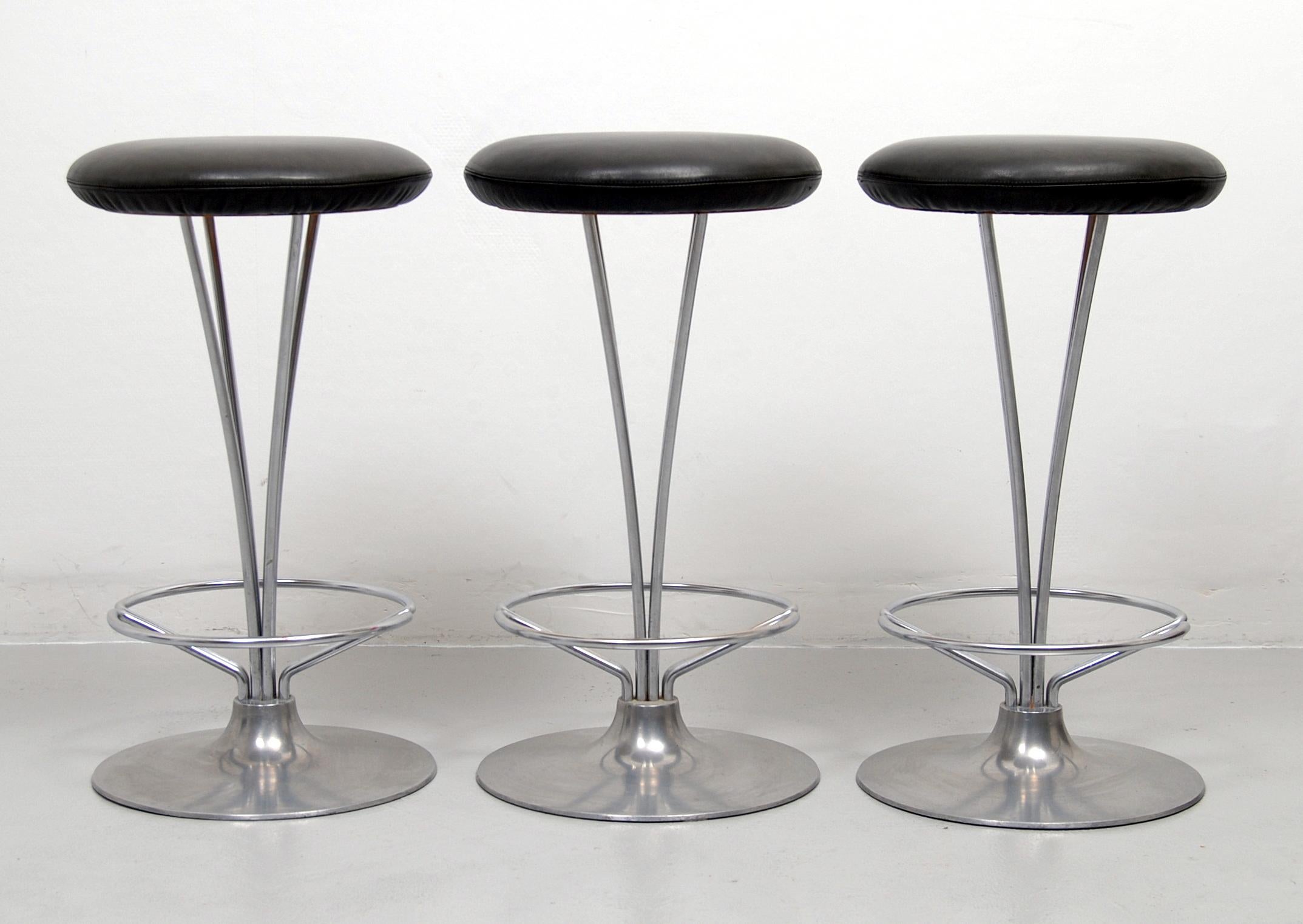 A set of three counter height / bar stools by Piet Hein for Fritz Hansen, Denmark. These stools have chrome-plated frames and a brushed aluminum base with new foam rubber and a light charcoal grey leather upholstery. All three labeled underneath;