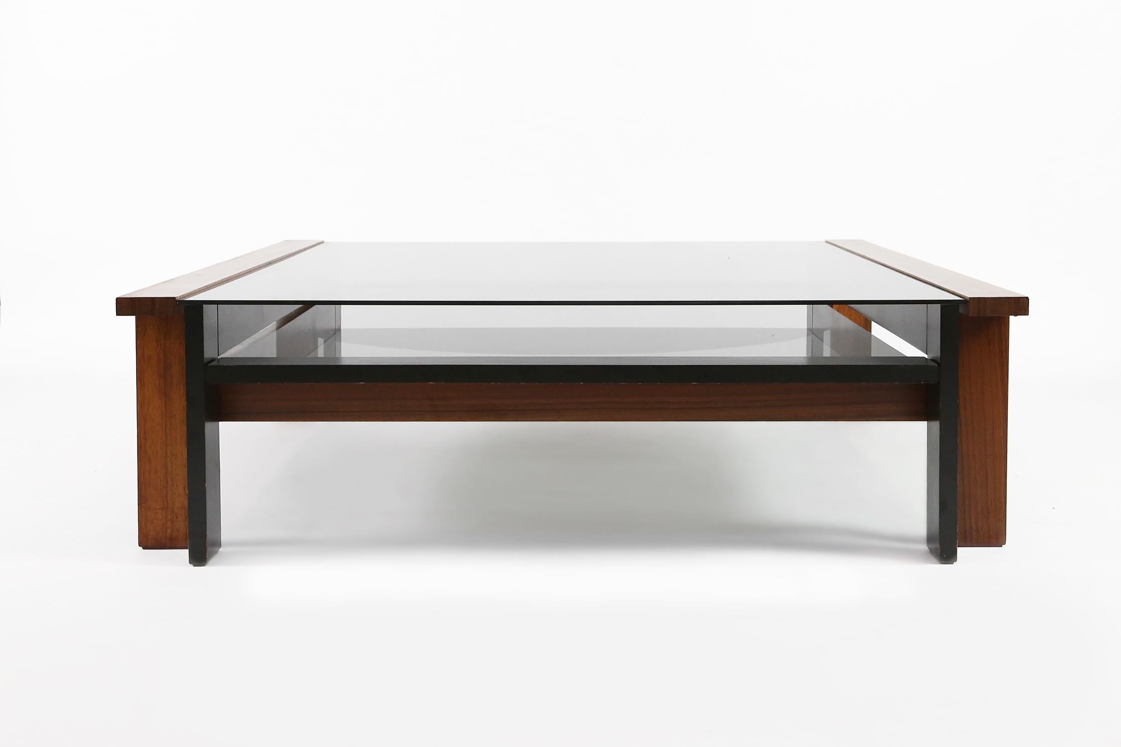 Exclusive coffee table designed by Pieter De Bruyne. The table dates from 1965, and has been produced in a very limited edition.
This table is made of Padauk wood, a part of the structure is ebonized. Structure in two levels. Fumed glass, lower