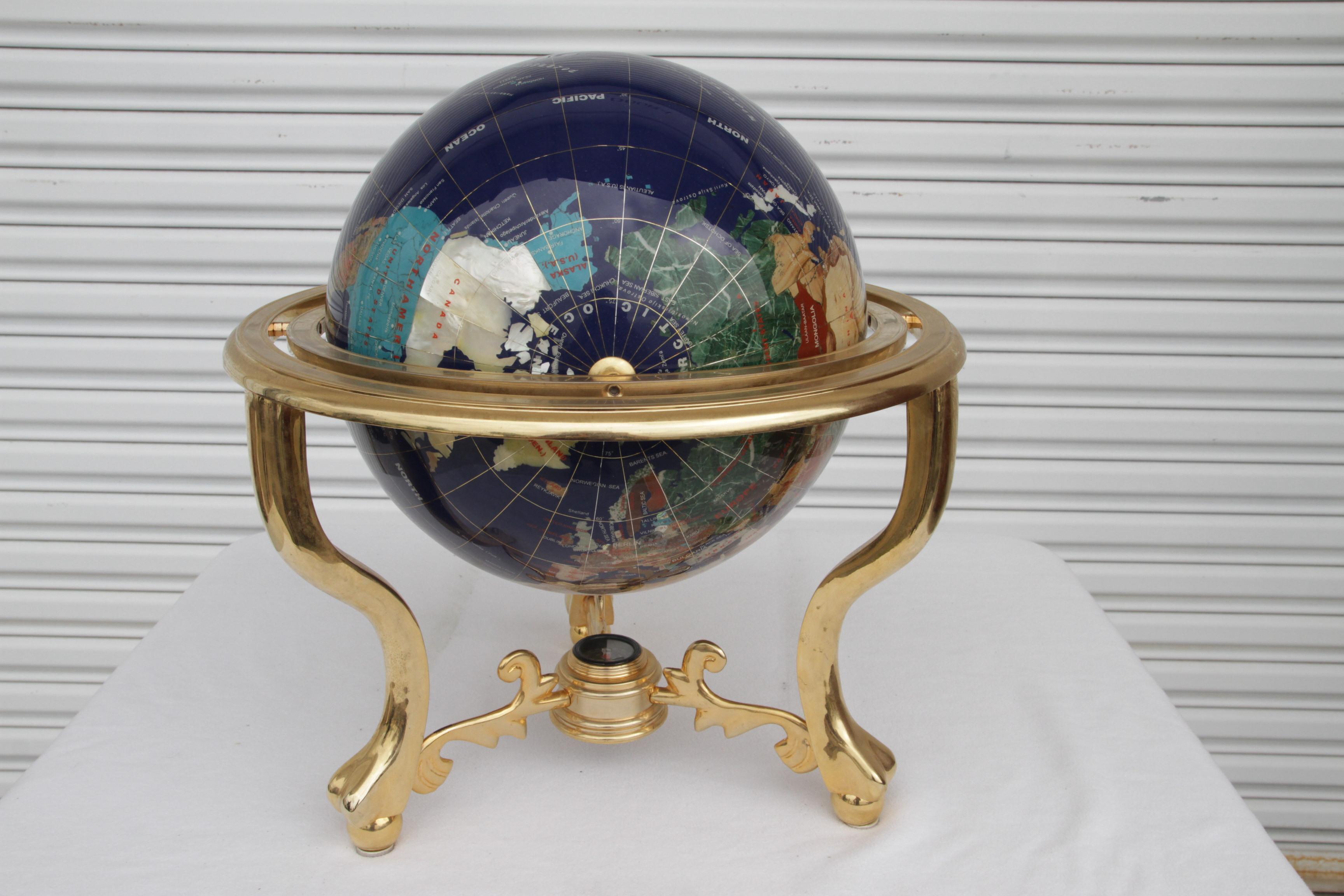 Globe captivant en Pietra Dura avec marbre, nacre et autres pierres semi-précieuses, suspendu à une monture en laiton massif. Le trépied en laiton tourne à 360 degrés et s'incline. La sphère est très lourde et solide, avec une boussole en dessous. 