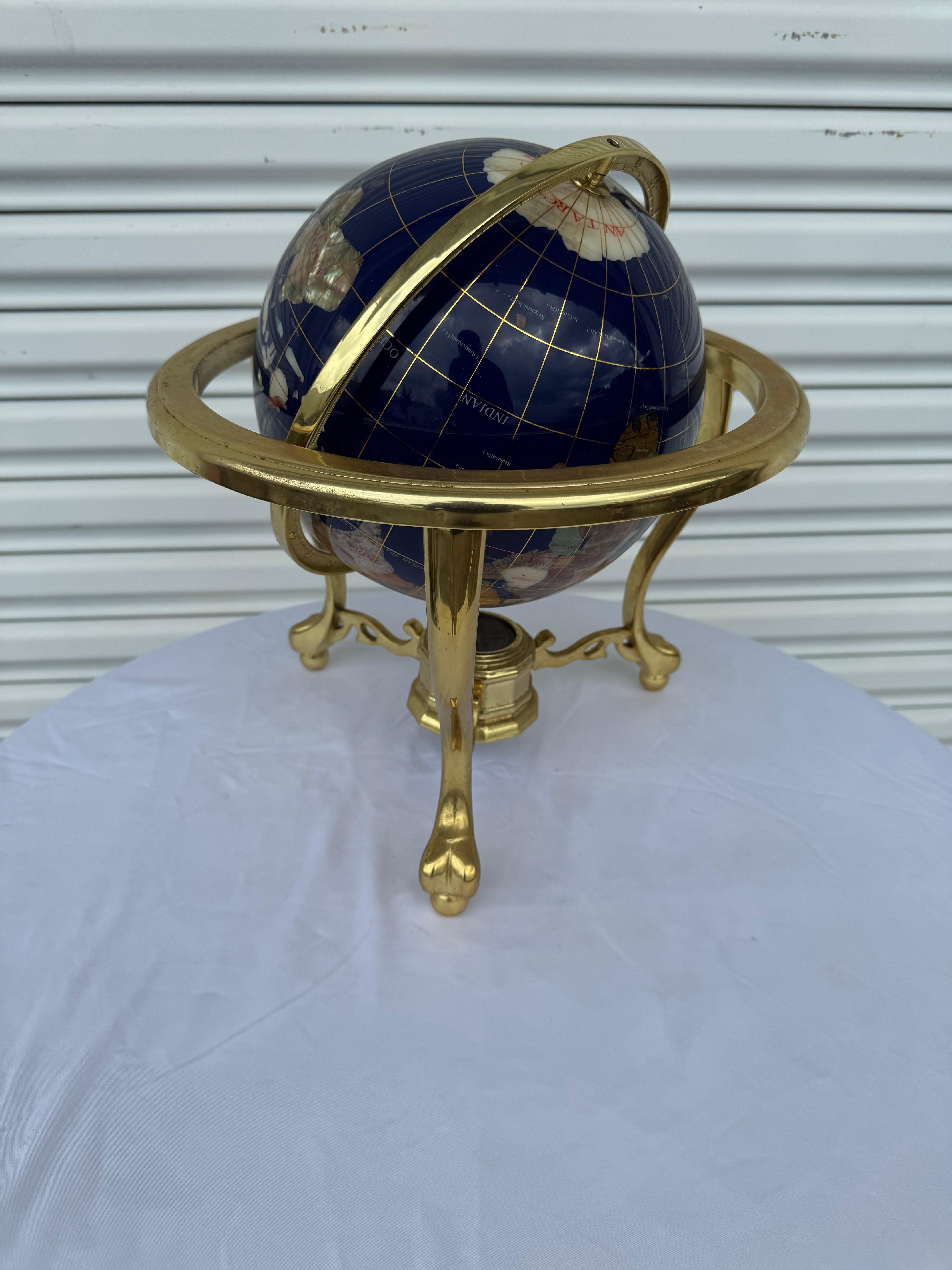 Captivating Pietra Dura globe featuring marble, mother-of-pearl and other semi-precious stones suspended in a solid brass mount. The brass tripod turns 360 degrees and tilts. The sphere is very heavy and solid with a compass below. 