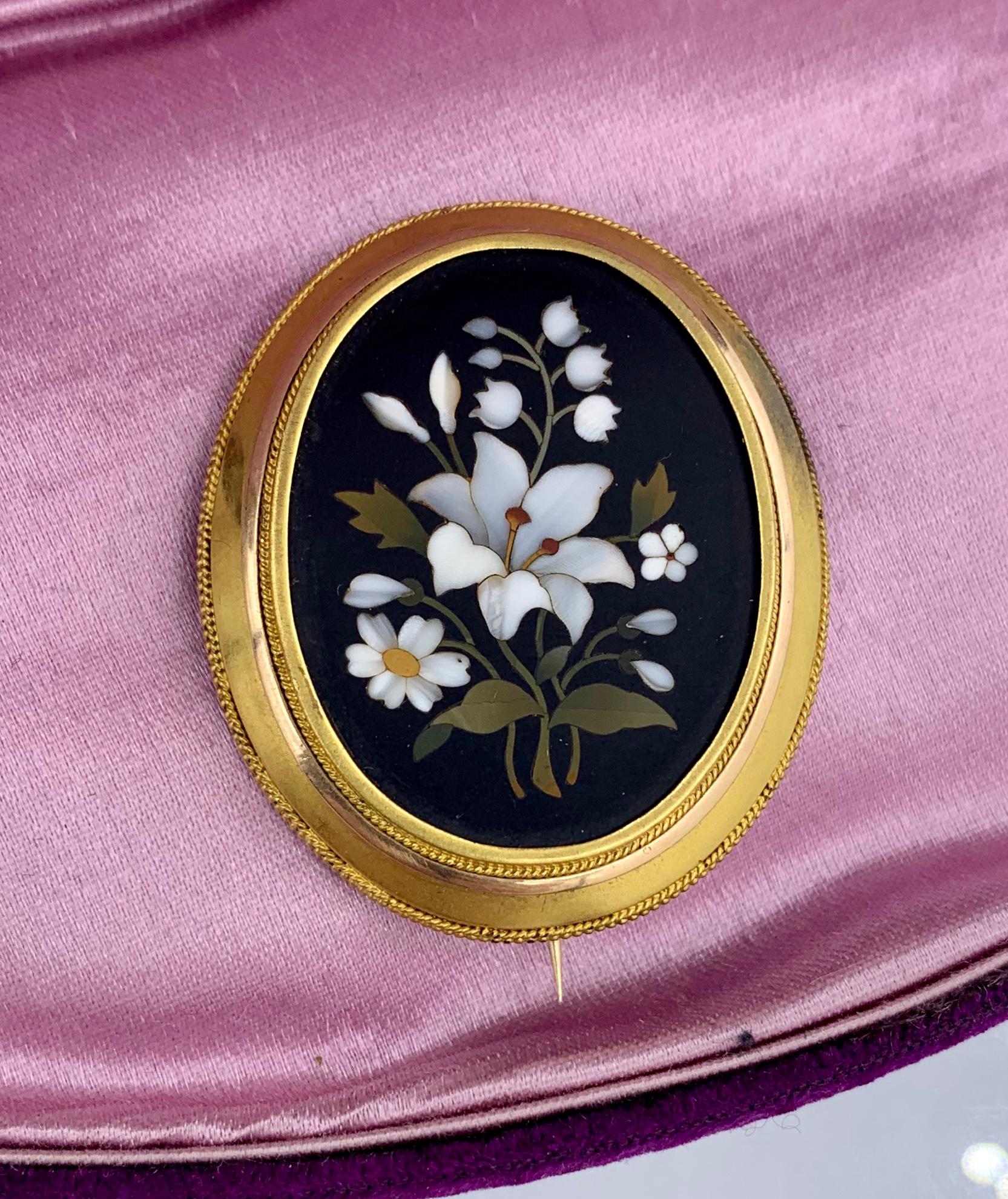 Eine atemberaubende Pietra Dura Brosche aus 14 Karat Gold mit eingelegten Halbedelsteinen, die ein Mosaikbild aus Blumen bilden, darunter eine wunderschöne weiße Lilie in der Mitte, Maiglöckchen, Gänseblümchen und Vergissmeinnicht.  Die Brosche ist