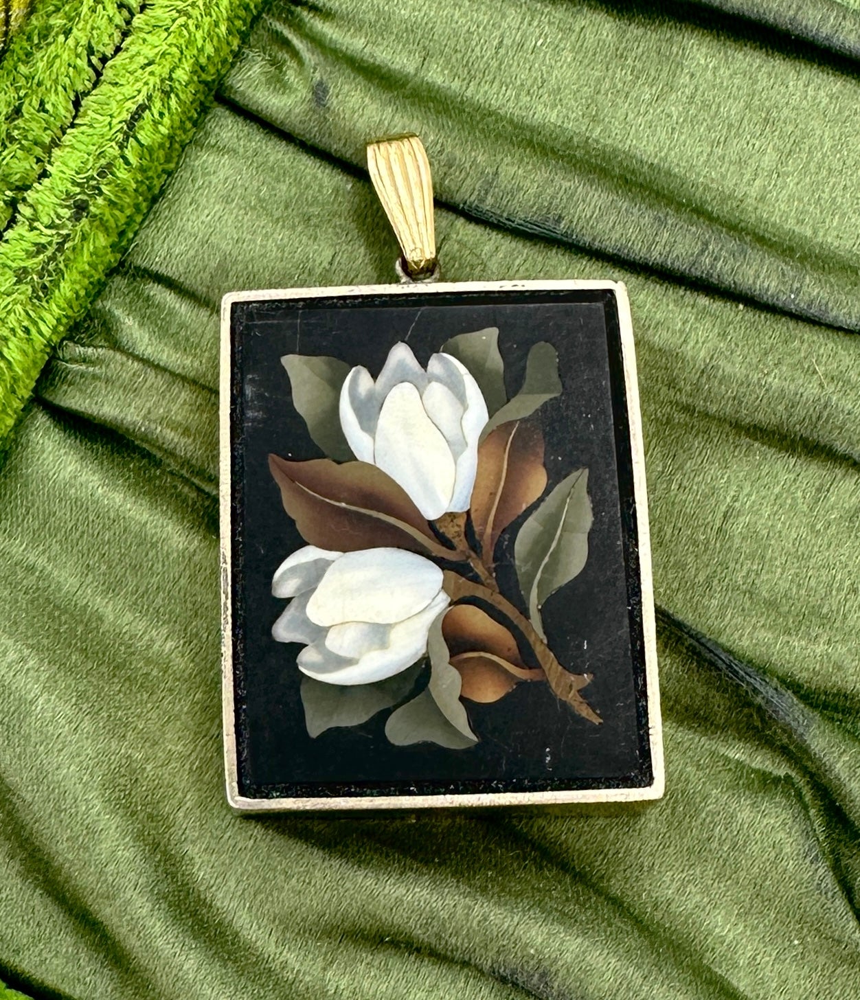 Indulge in a stunning antique Pietra Dura Pendant in Gold with inlaid semi-precious stones creating a mosaic image of lily flowers.  The pendant is a masterpiece of Pietra Dura work.  The vivid creamy white flowers and green leaves set against the