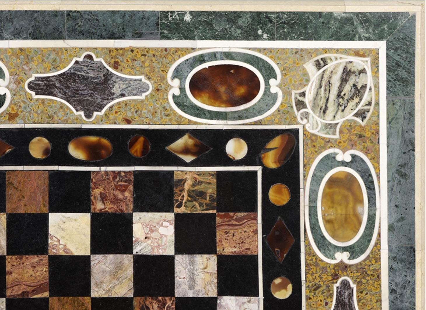 An outer band of framed oval agates interspersed with shields in the corners and rhomboidal forms highlights the central area, which has a chessboard in different colored stones and other blacks, an area that has been highlighted by a band of simple