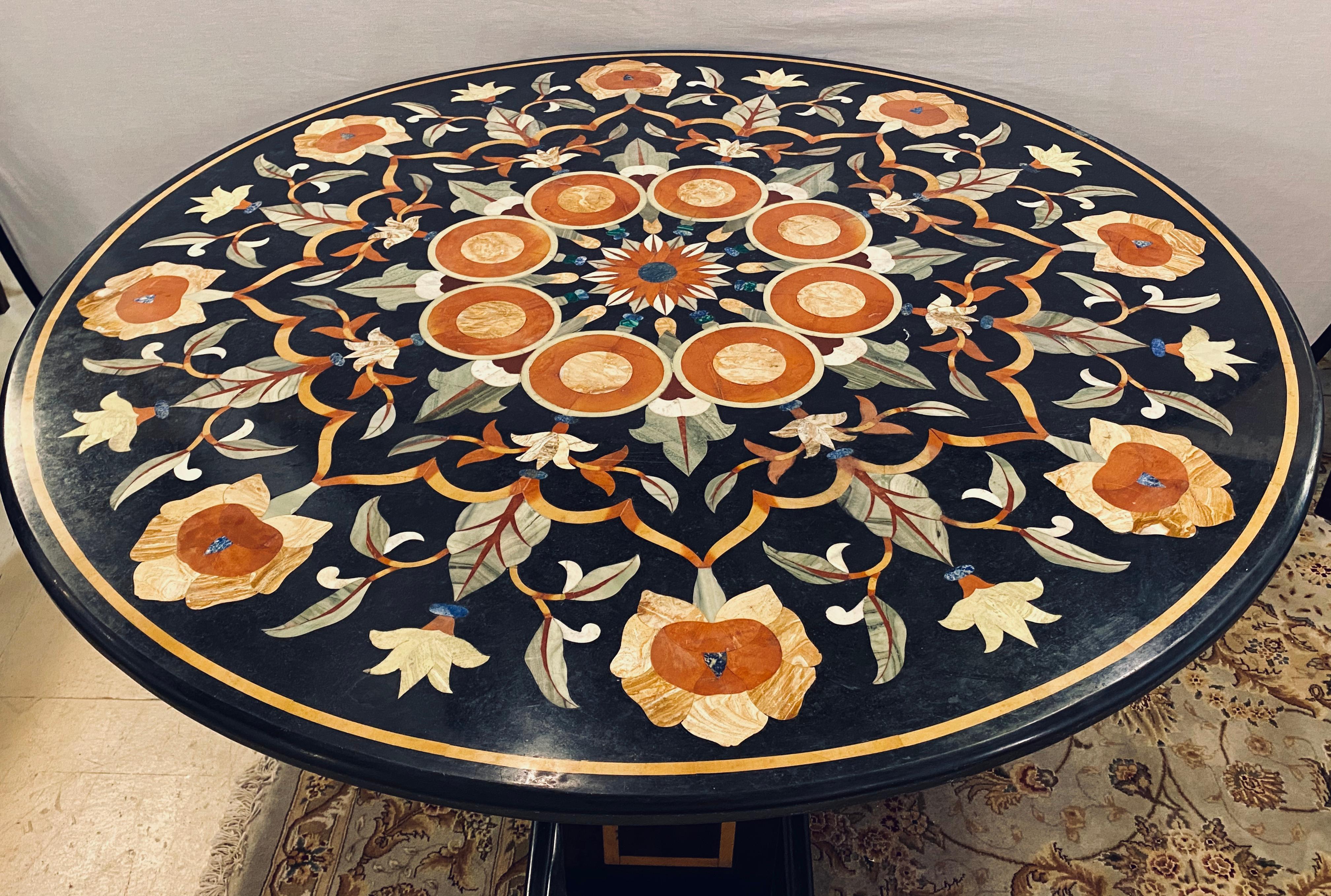 Pietra dura marble top dining or center table with marble ebony inlaid pedestal base. The finely cut and inlaid marble table top is 1.5 inches thick with rounded edges and is 48 inches in diameter. This stunning center or dining table is one of two